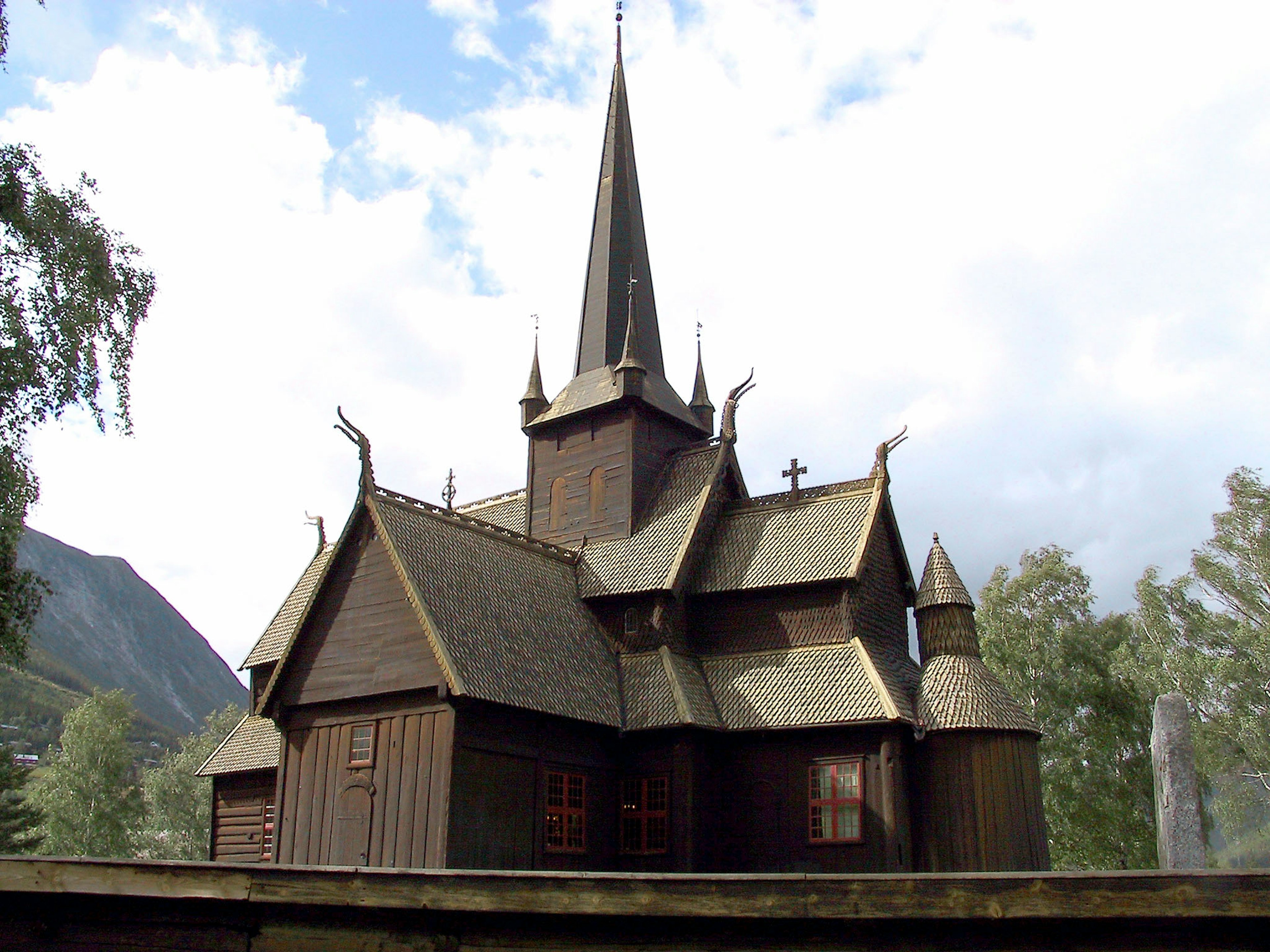 Beautiful wooden church with spires and intricate roof design surrounded by green trees under a blue sky