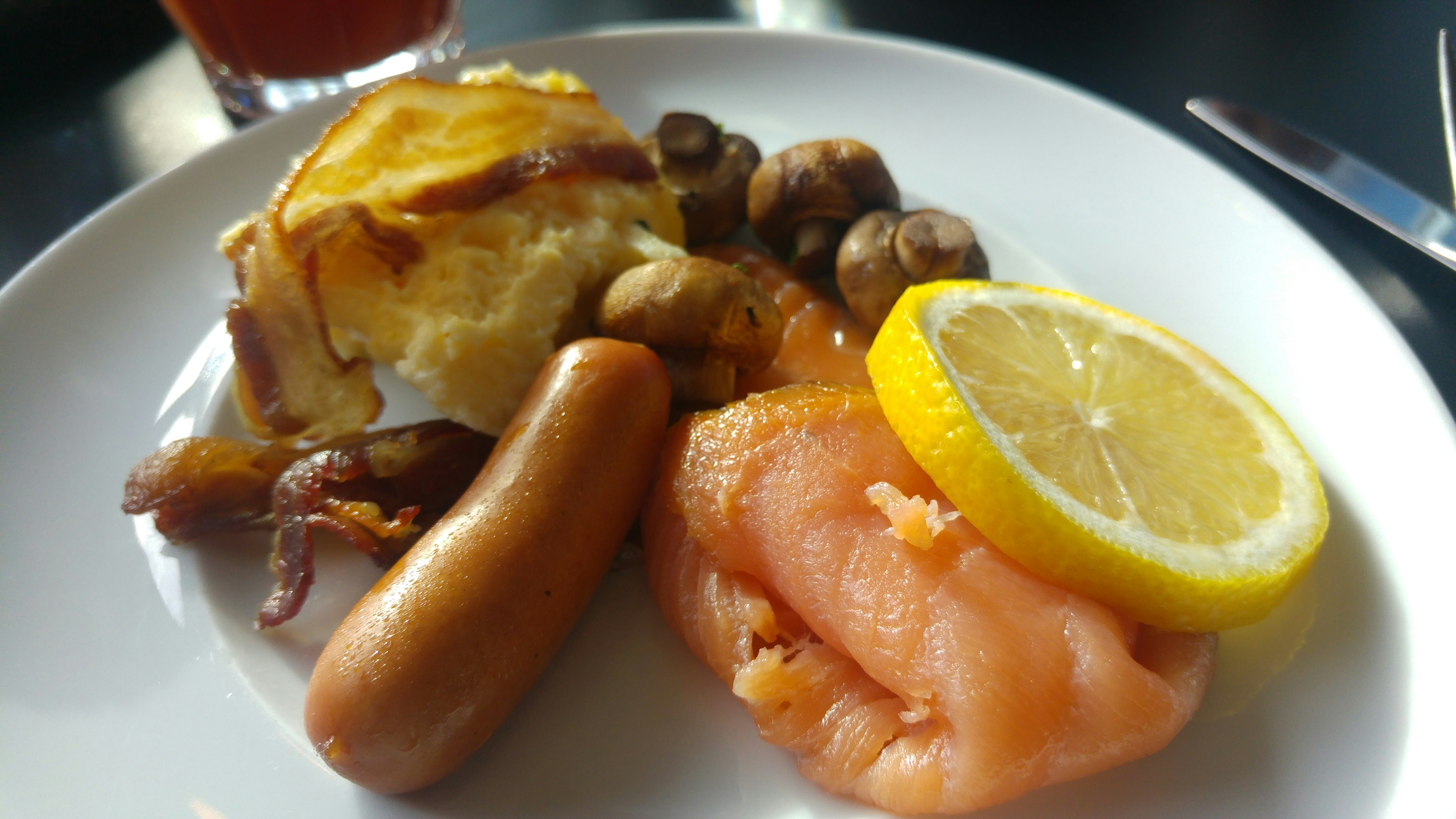 Plato de desayuno con salchicha salmón ahumado rodaja de limón champiñones y tortilla