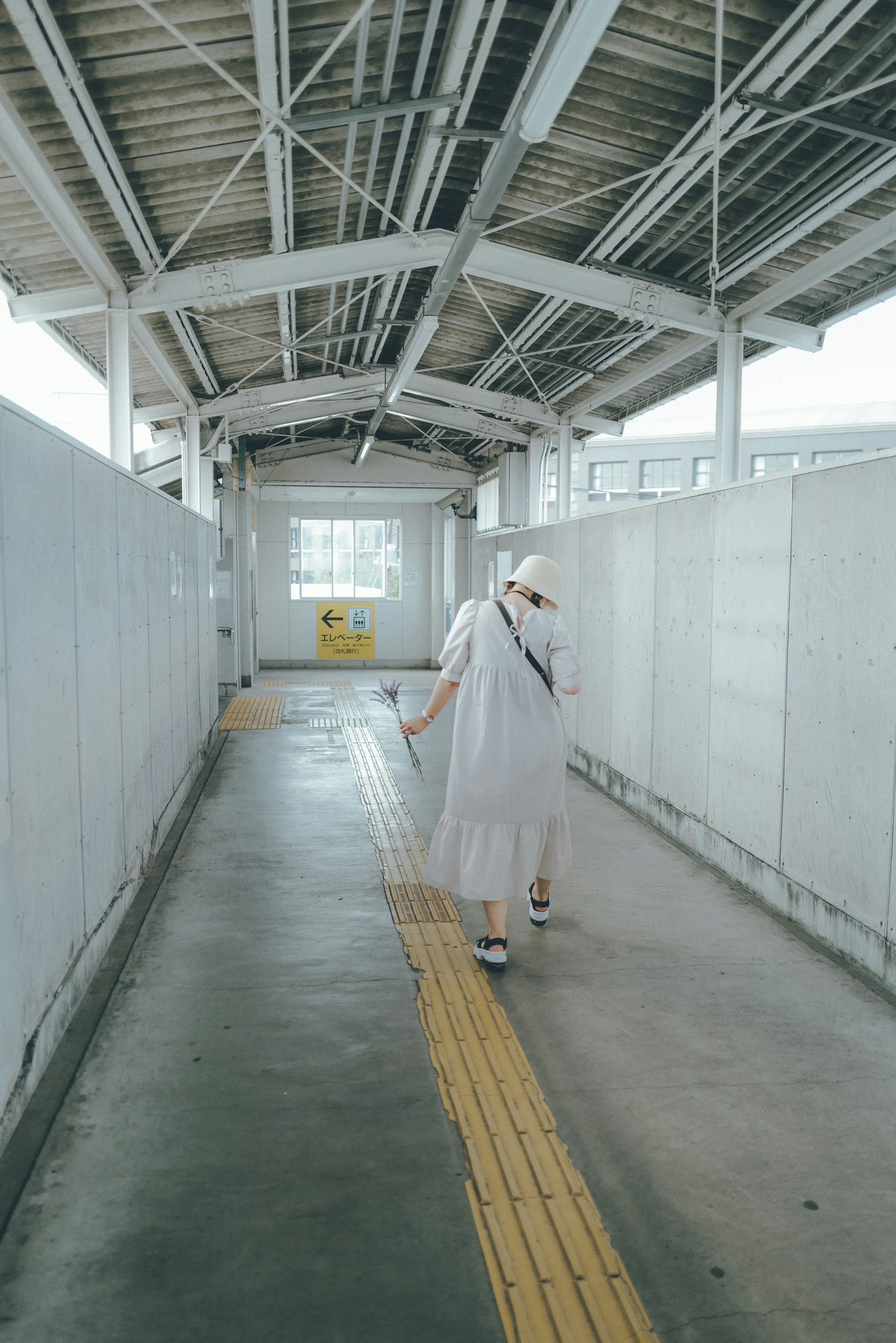 Person in white clothing walking down a long corridor