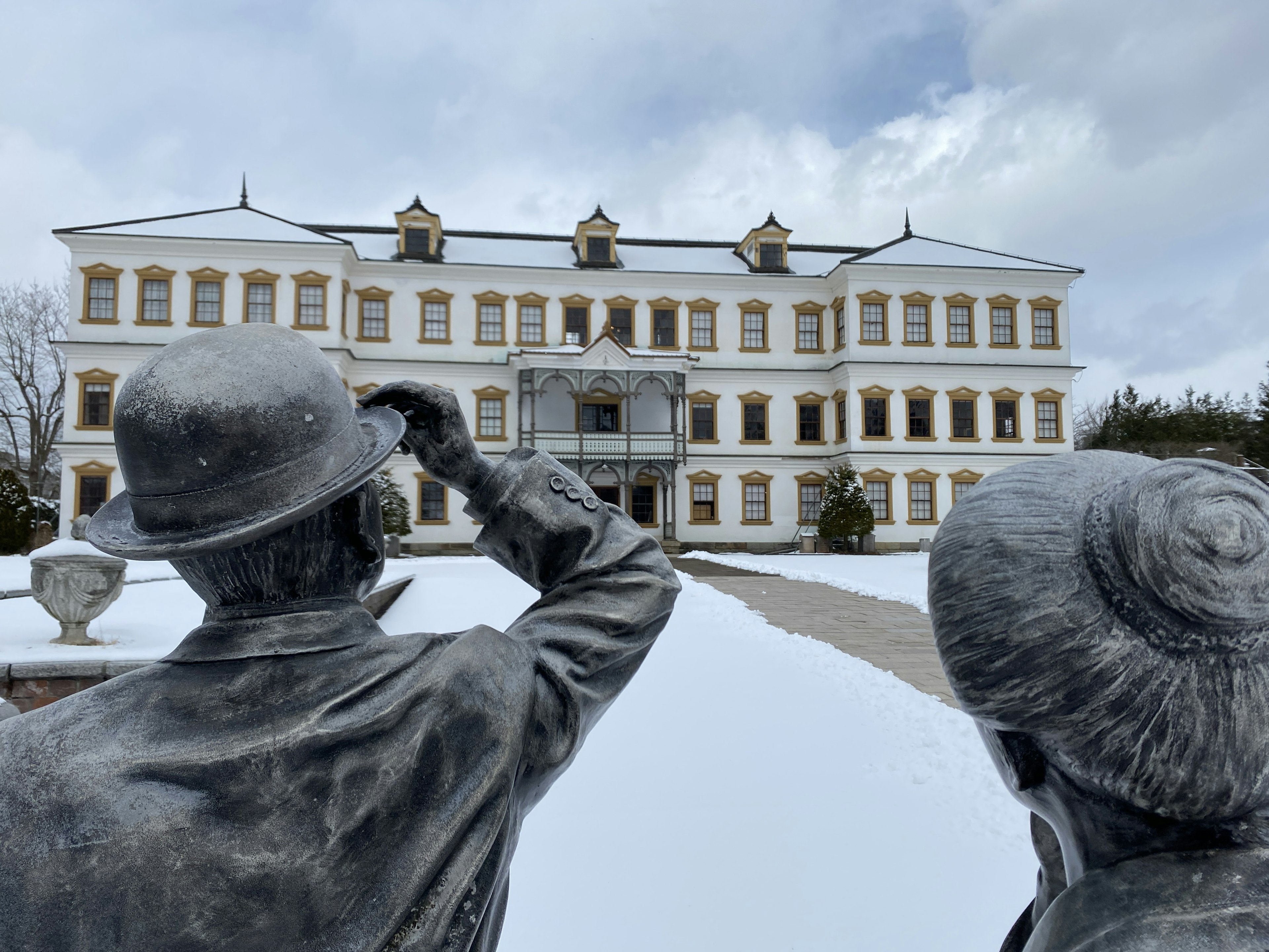 Zwei Skulpturen, die auf ein großes, mit Schnee bedecktes Gebäude schauen