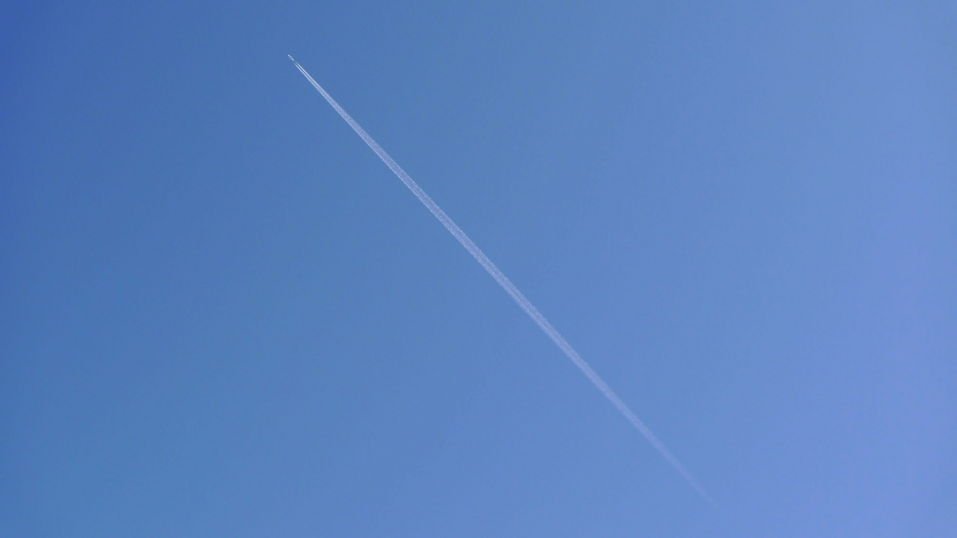 A single contrail visible in a clear blue sky