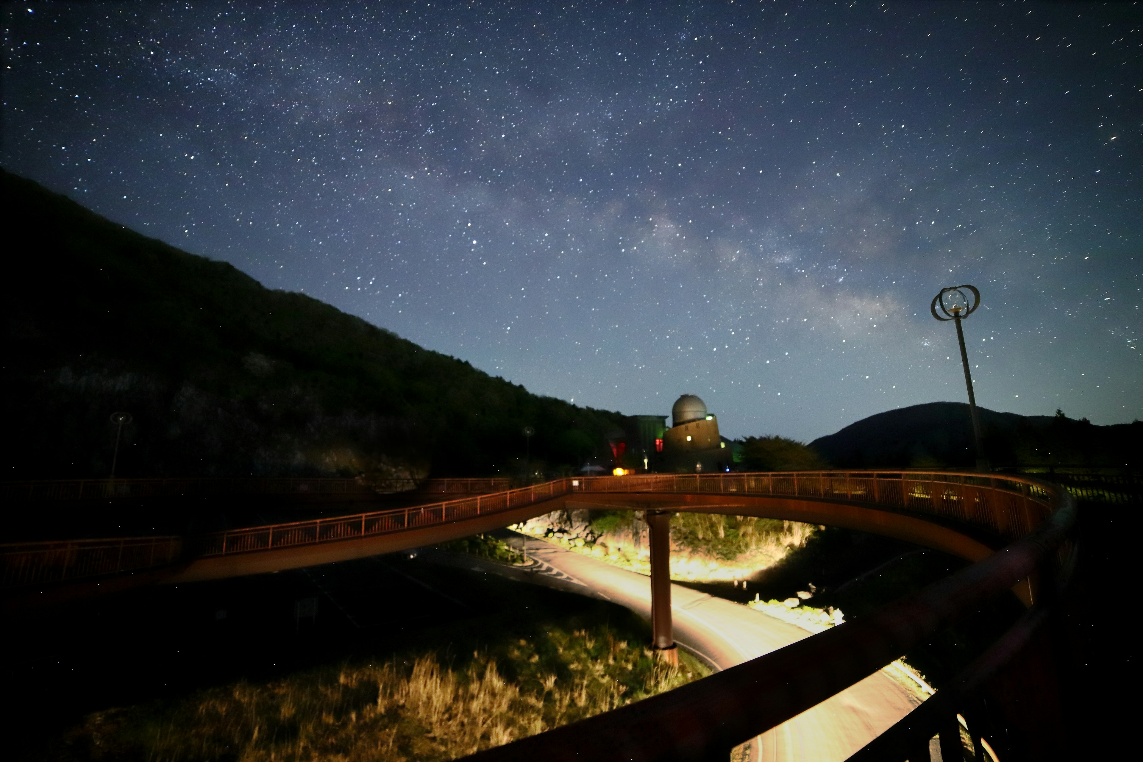 Pont en bois sous un ciel étoilé avec arrière-plan montagneux