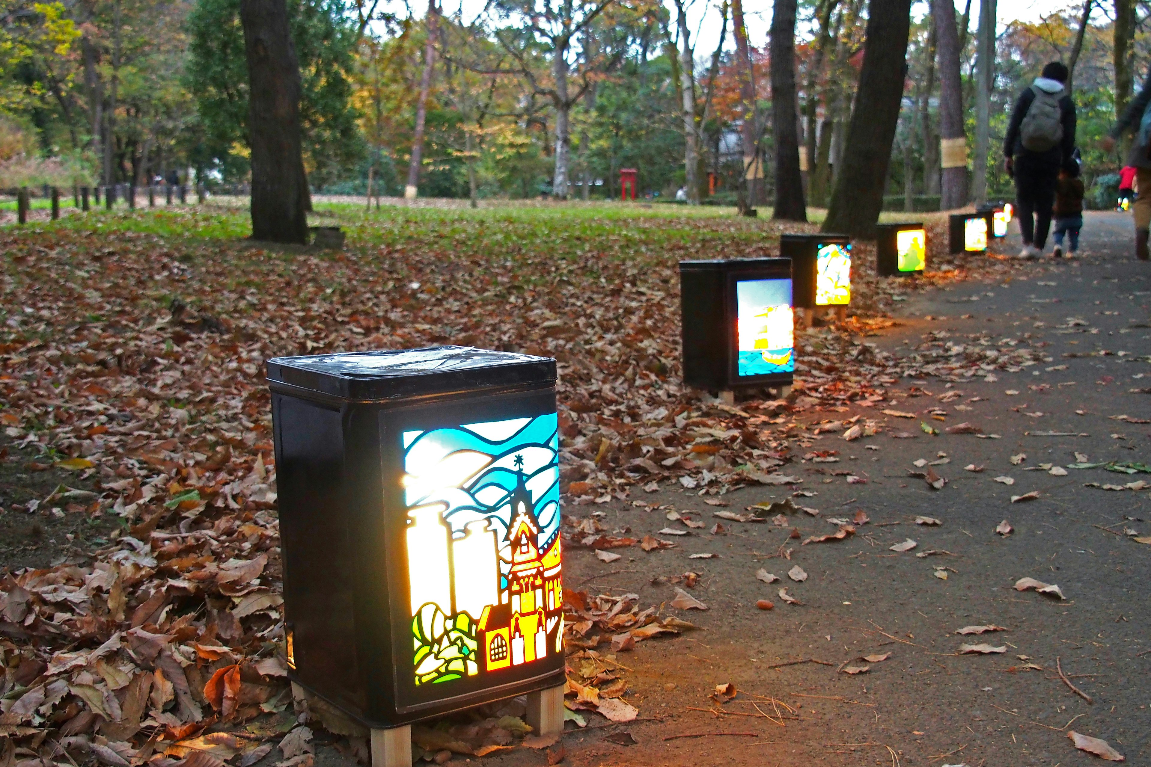 Lampes colorées alignées le long d'un chemin dans un parc d'automne avec des feuilles tombées