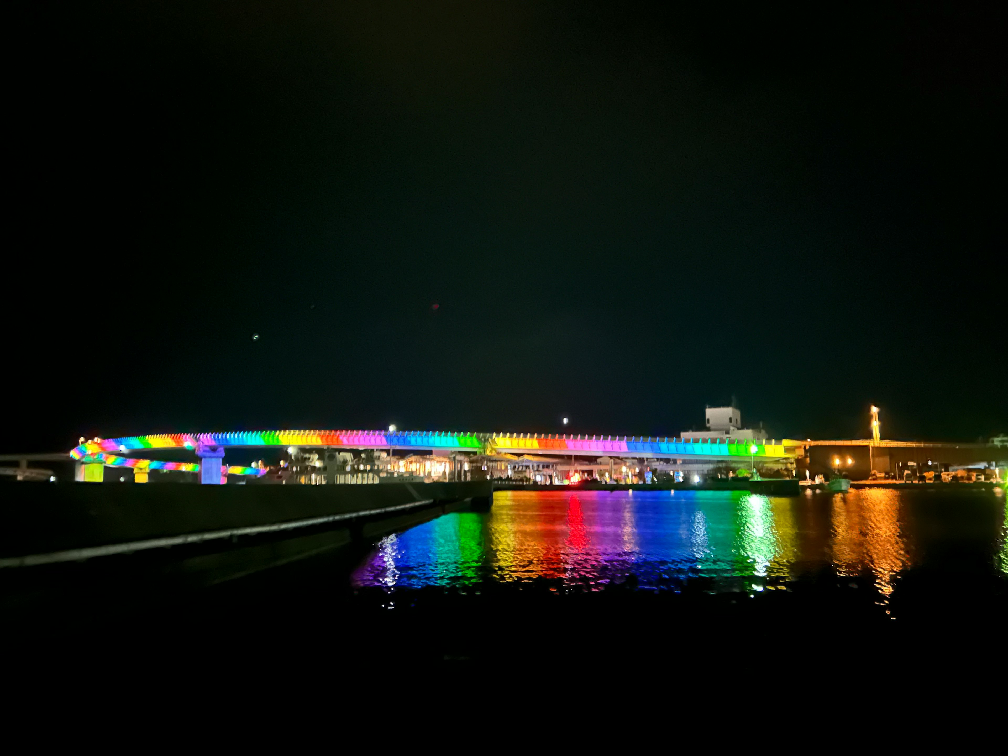 Colorful illuminated bridge reflecting on water at night