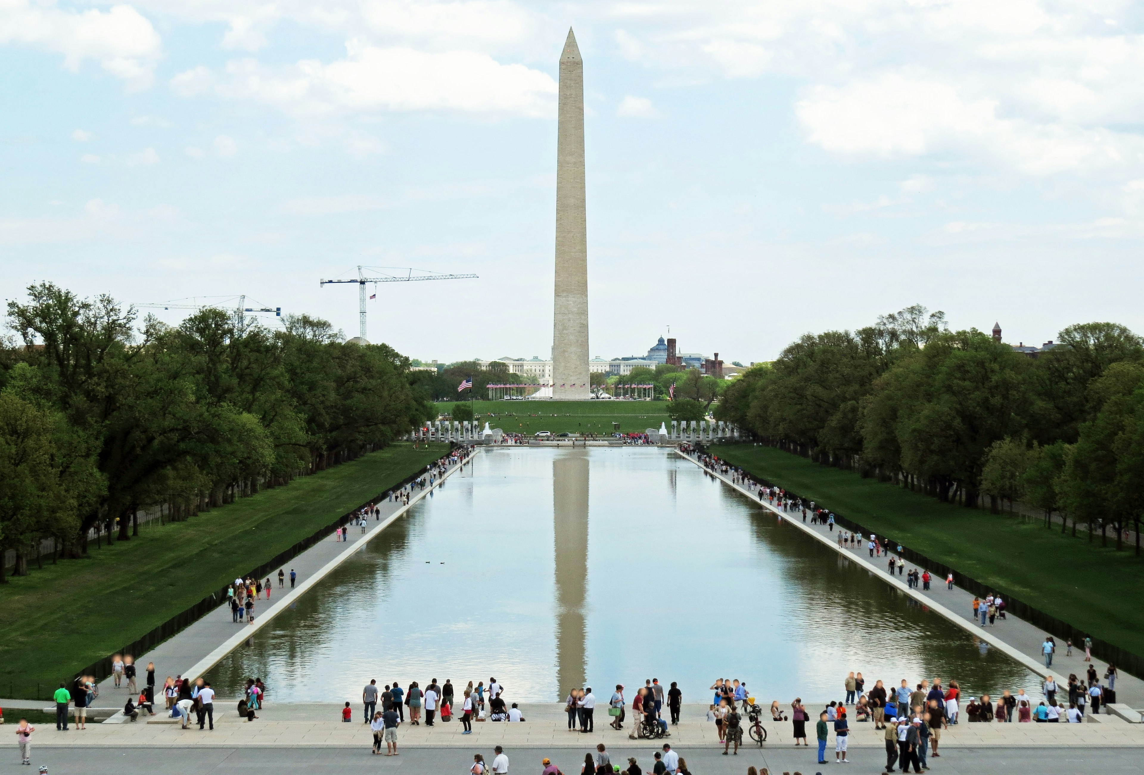 View of the Washington Monument with a reflecting pool and numerous visitors