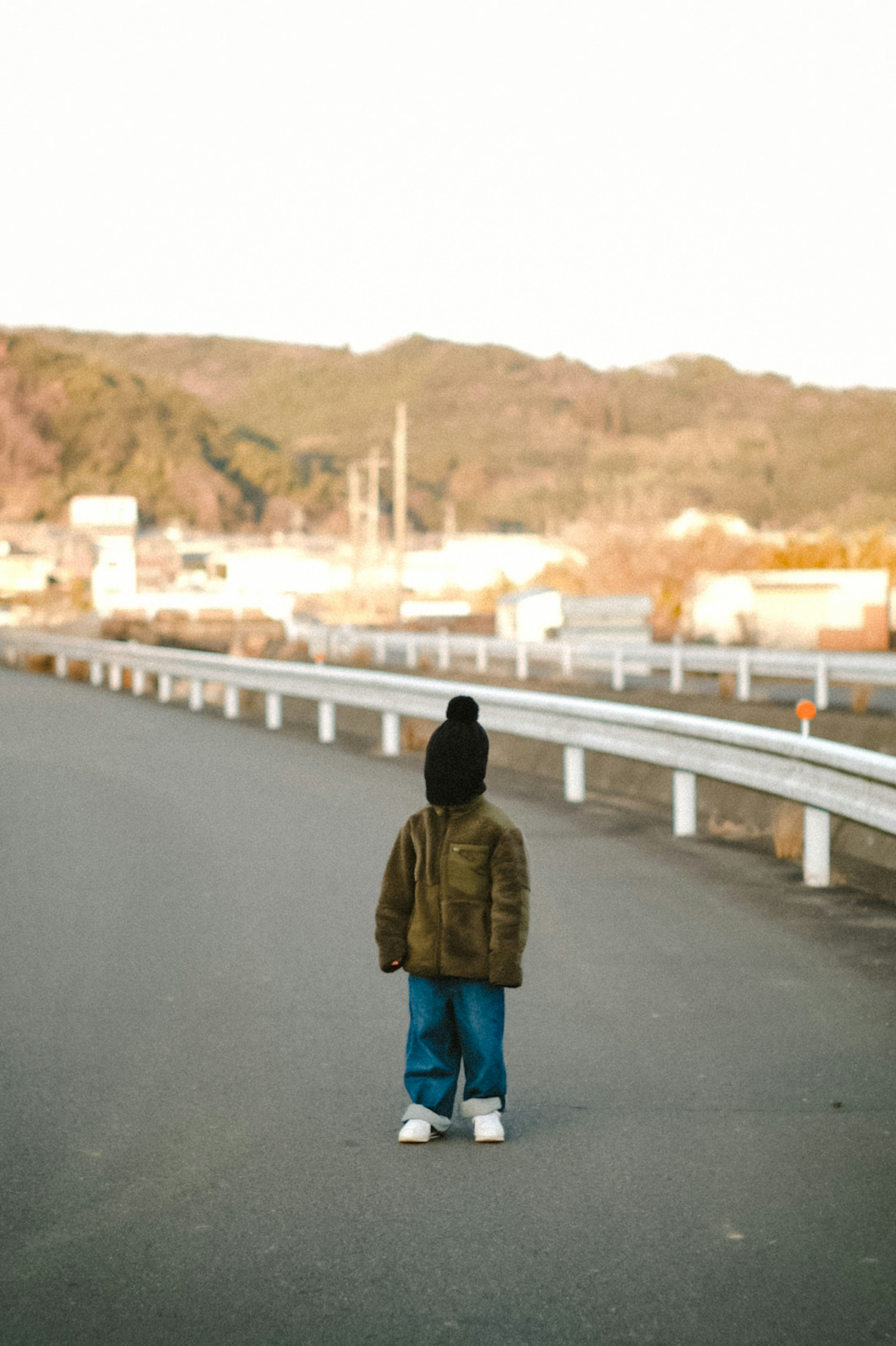 孩子站在馬路上，背景是日落時的山脈