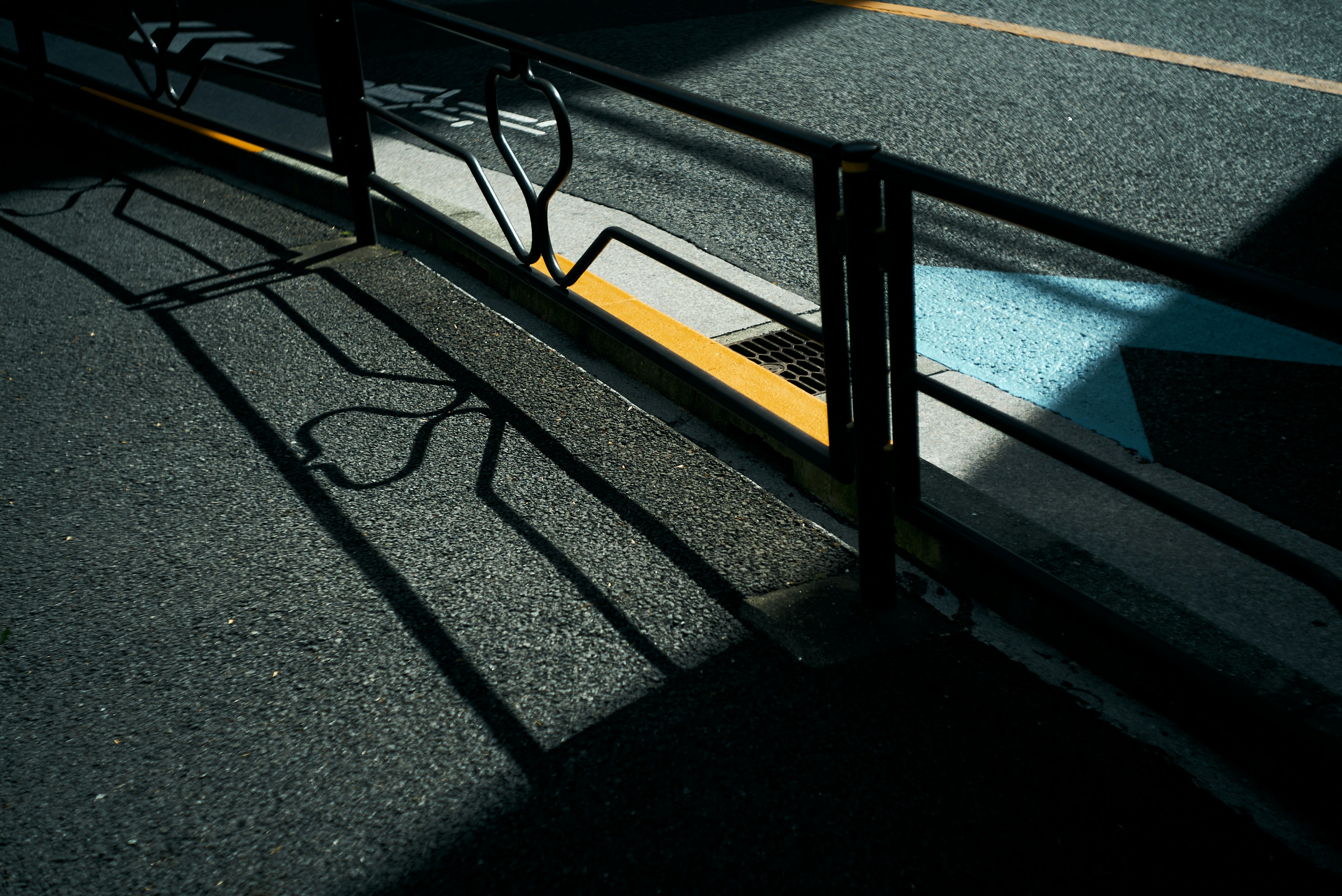 Shadows of a railing on a street with contrasting light