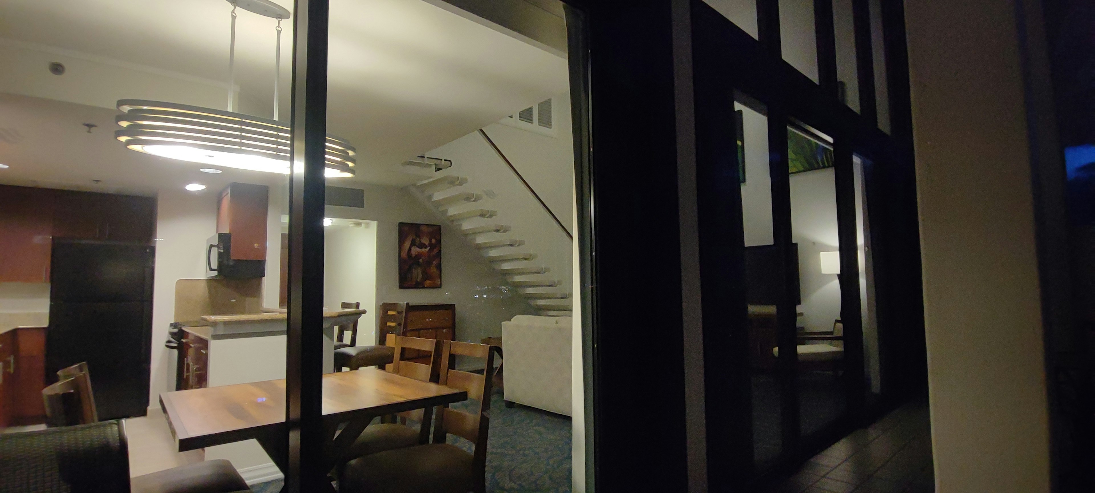 Interior photo of a modern living room and dining area featuring distinctive lighting table and chairs visible staircase