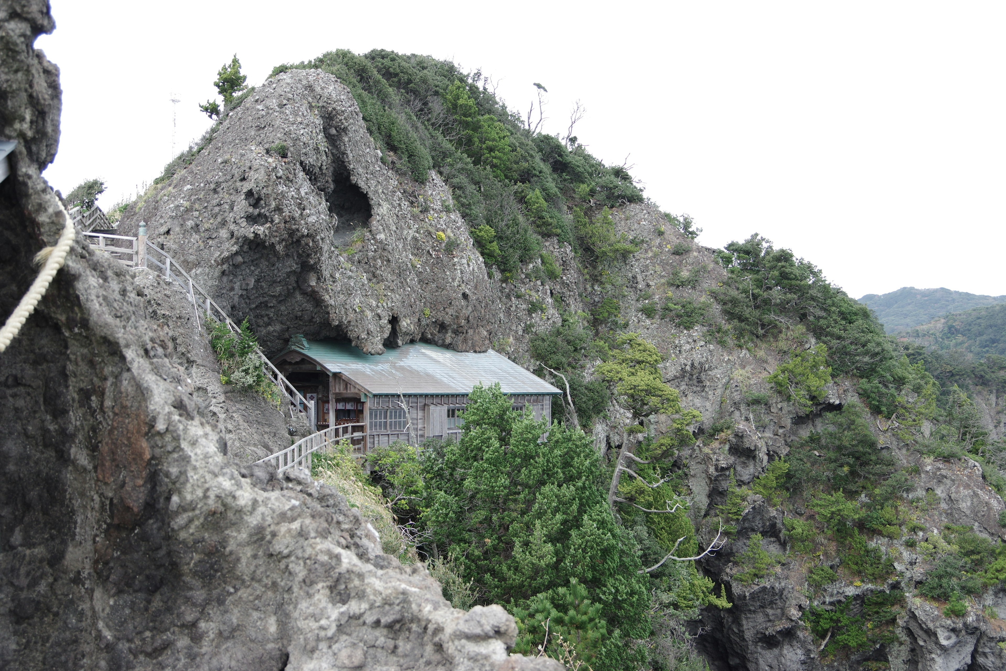 Eine kleine Hütte auf einer felsigen Klippe umgeben von Grün