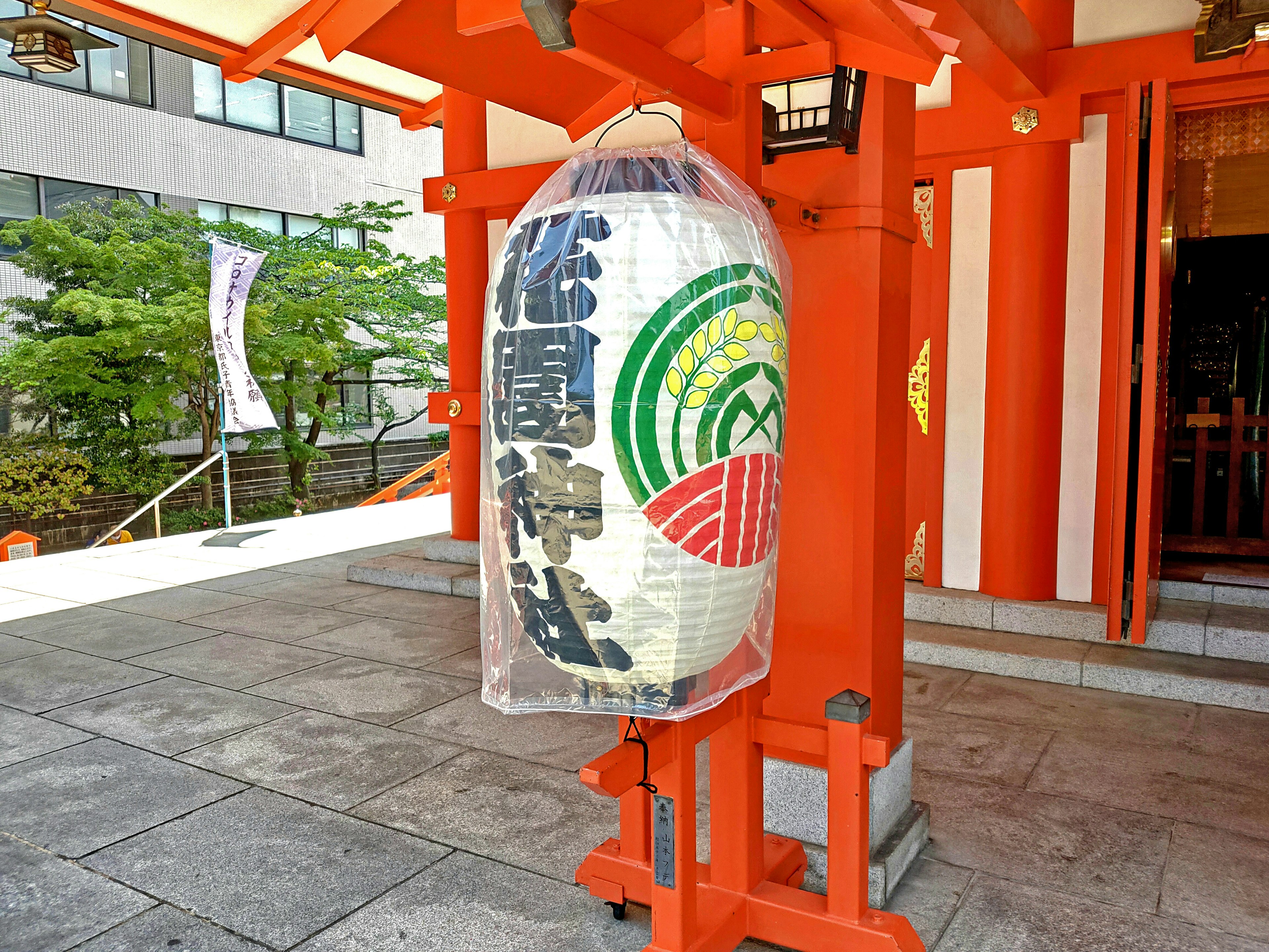 Large traditional lantern with colorful designs near a red torii gate