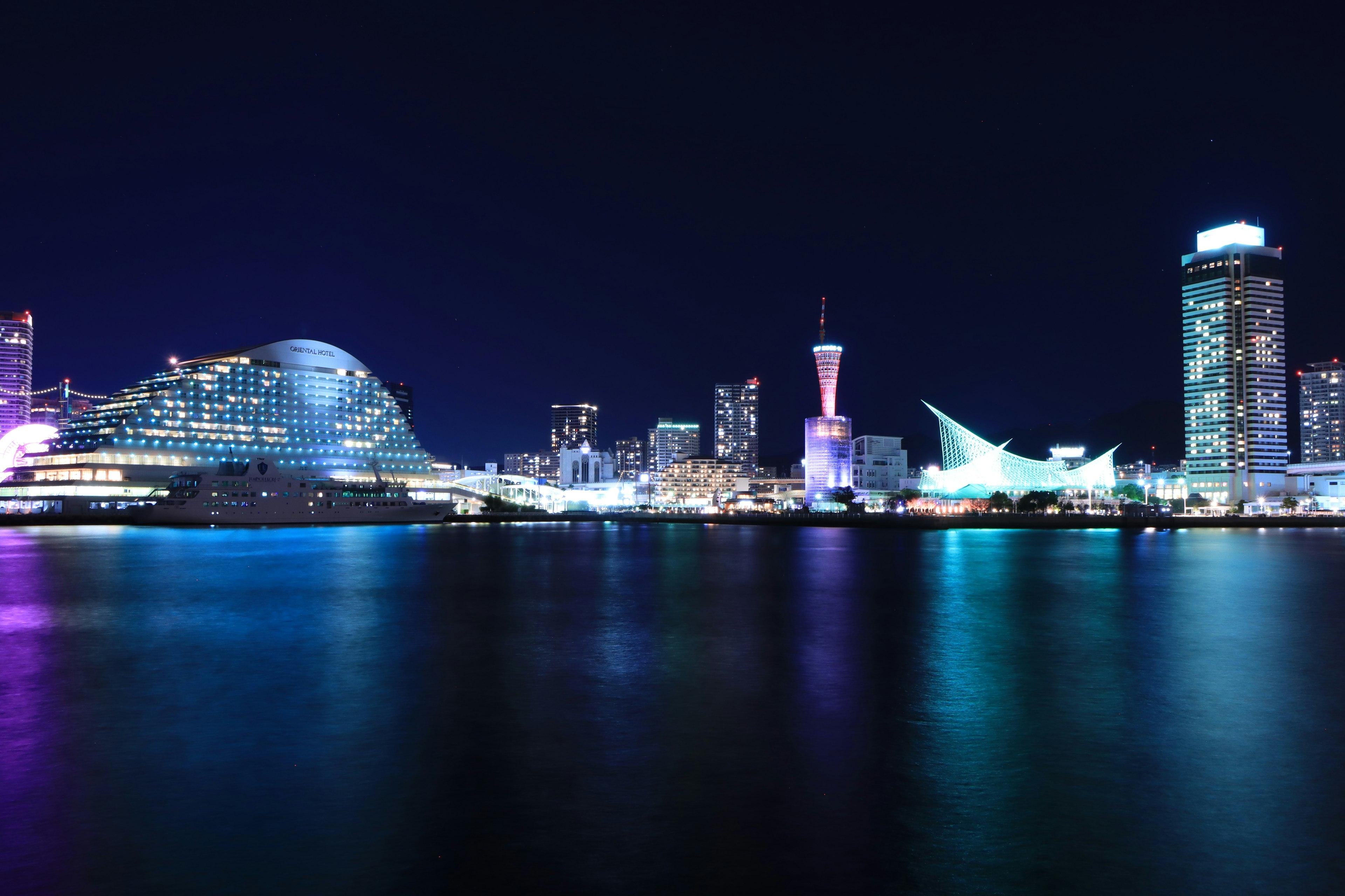 Garis langit Yokohama di malam hari dengan bangunan yang diterangi dan air reflektif