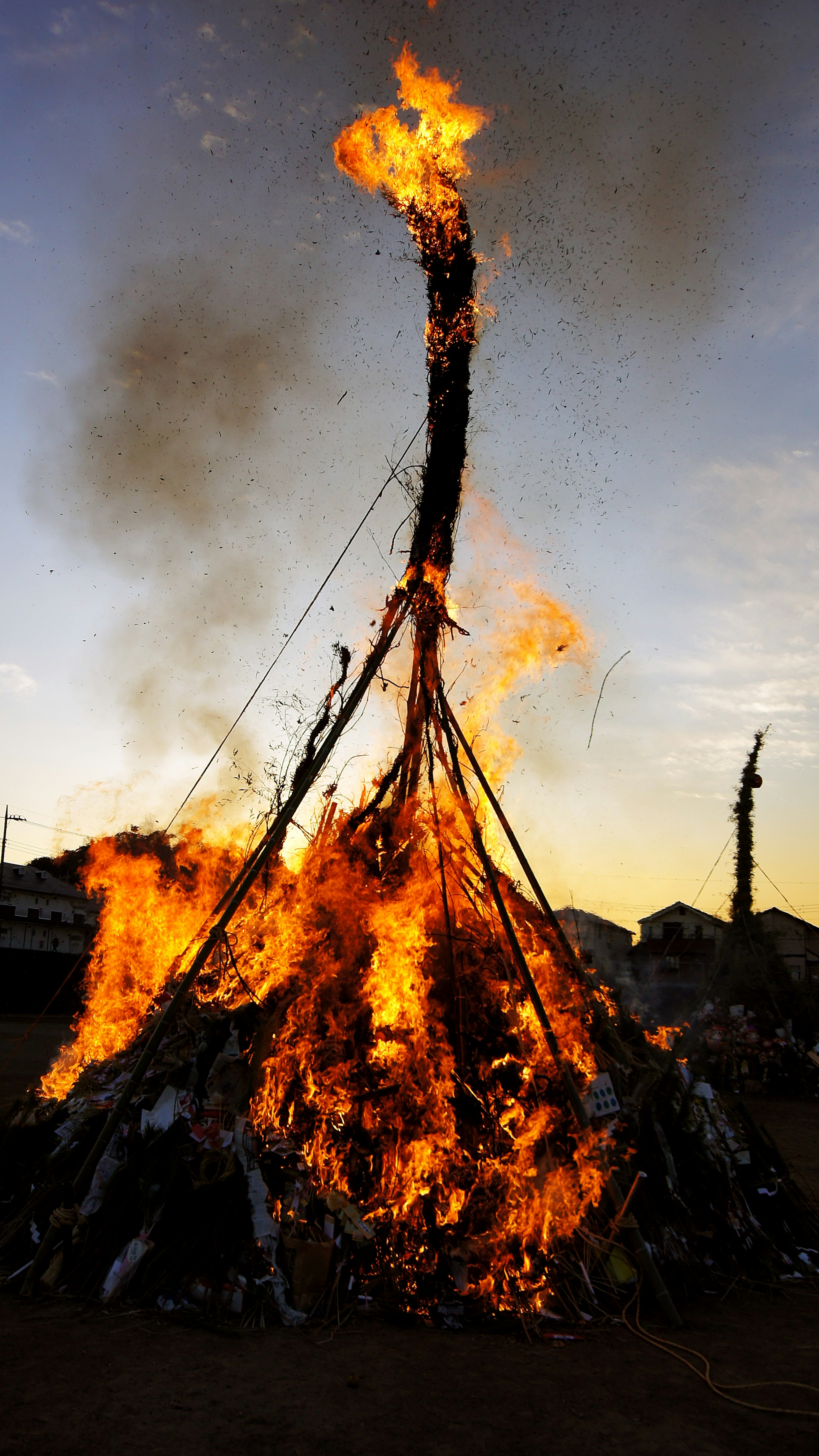 Grande falò con fiamme che si ergono contro un cielo al tramonto