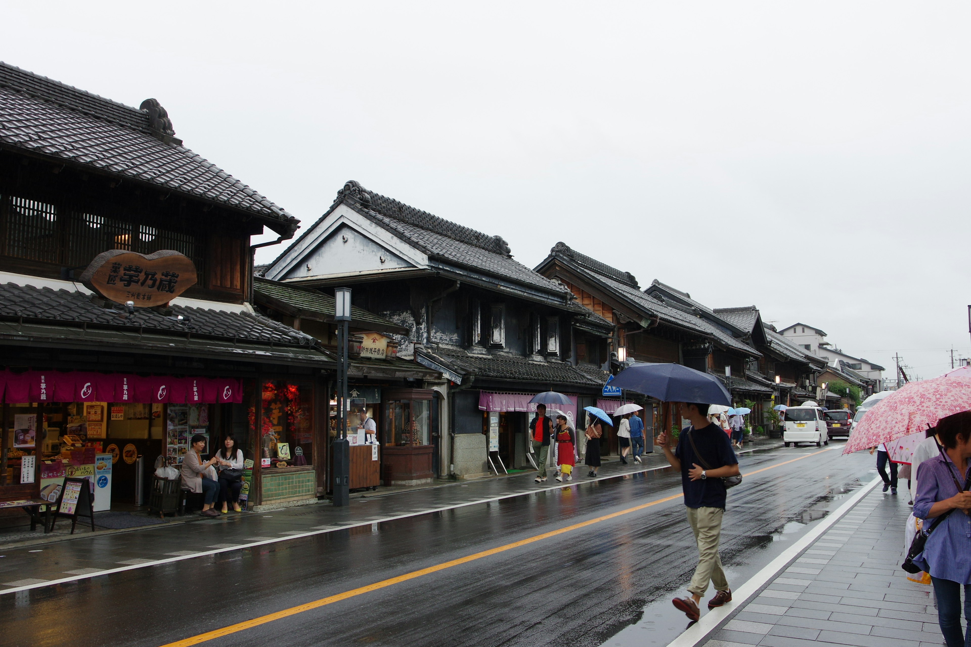 Traditionelle japanische Straßenansicht an einem regnerischen Tag mit Menschen, die Regenschirme halten