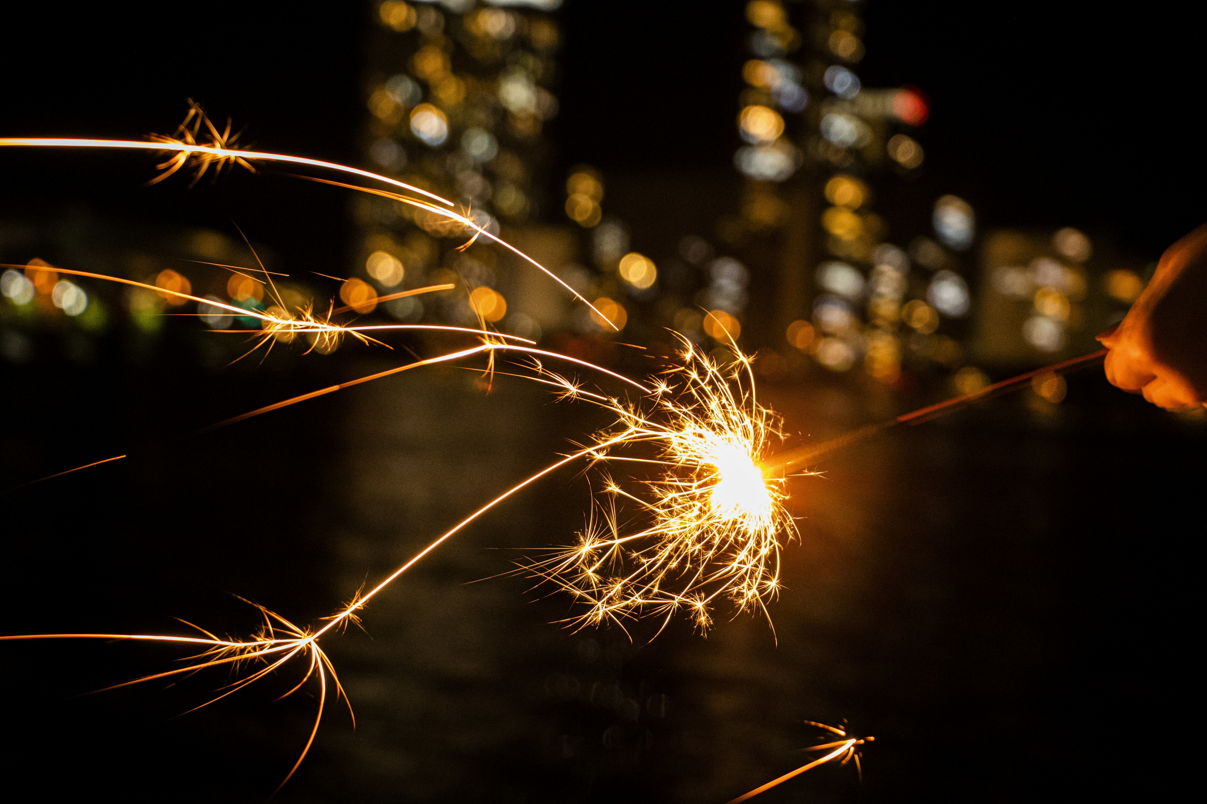 Sprühkerze leuchtet in der Nacht mit verschwommenen Lichtern der Stadt im Hintergrund