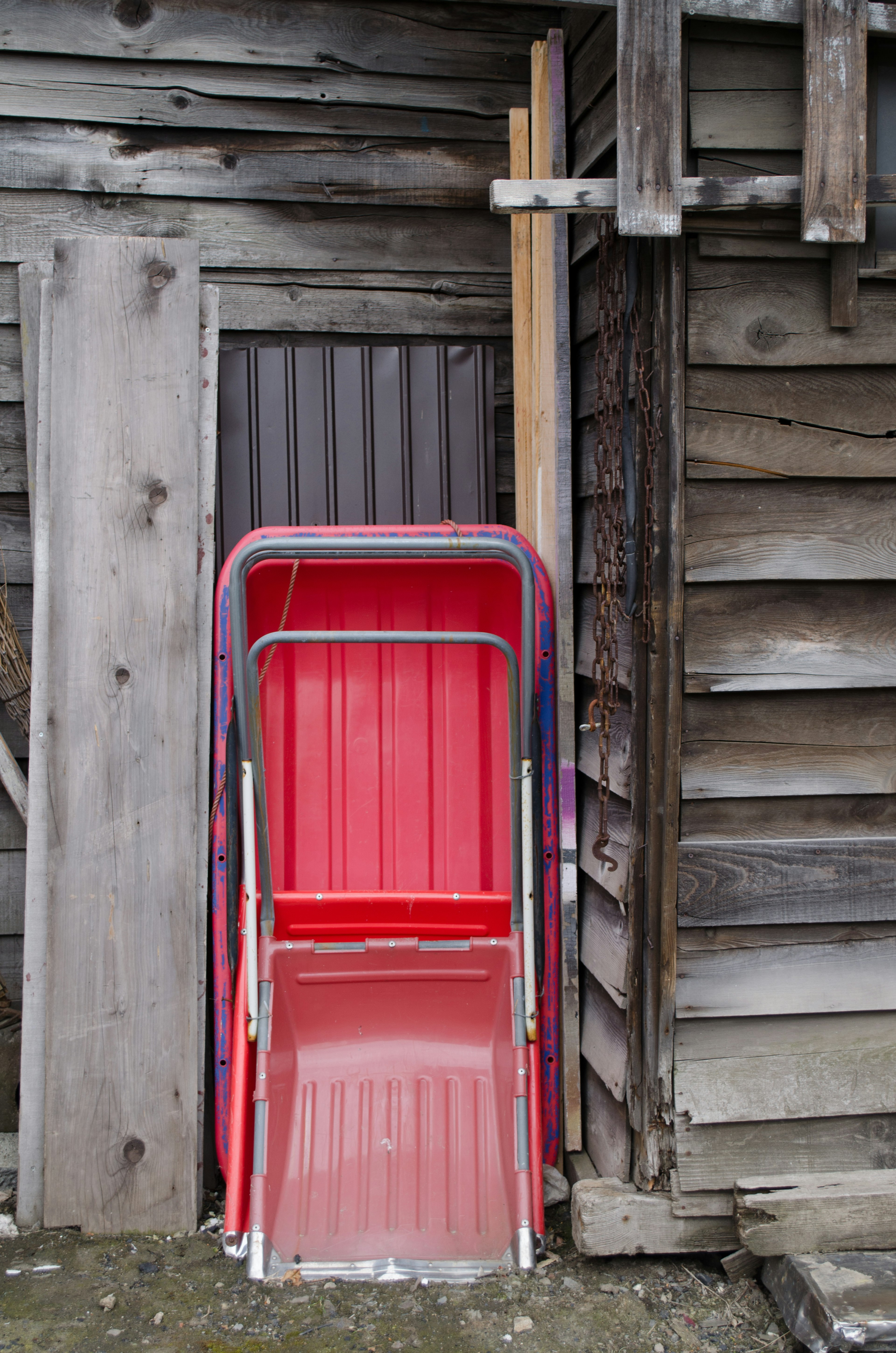 Red slide leaning against a wooden shed