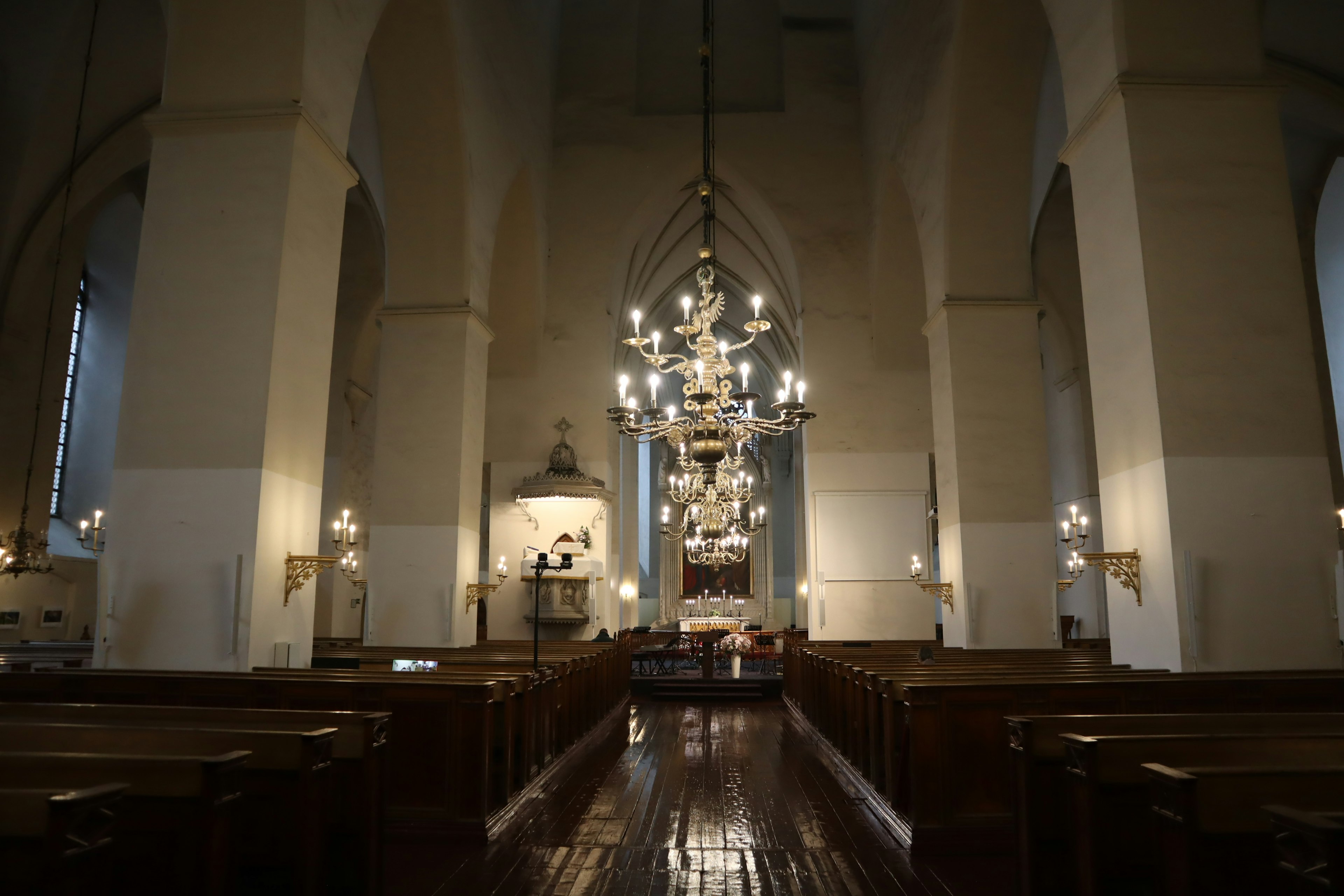 Interior of a church featuring a beautiful chandelier wooden pews and a bright atmosphere