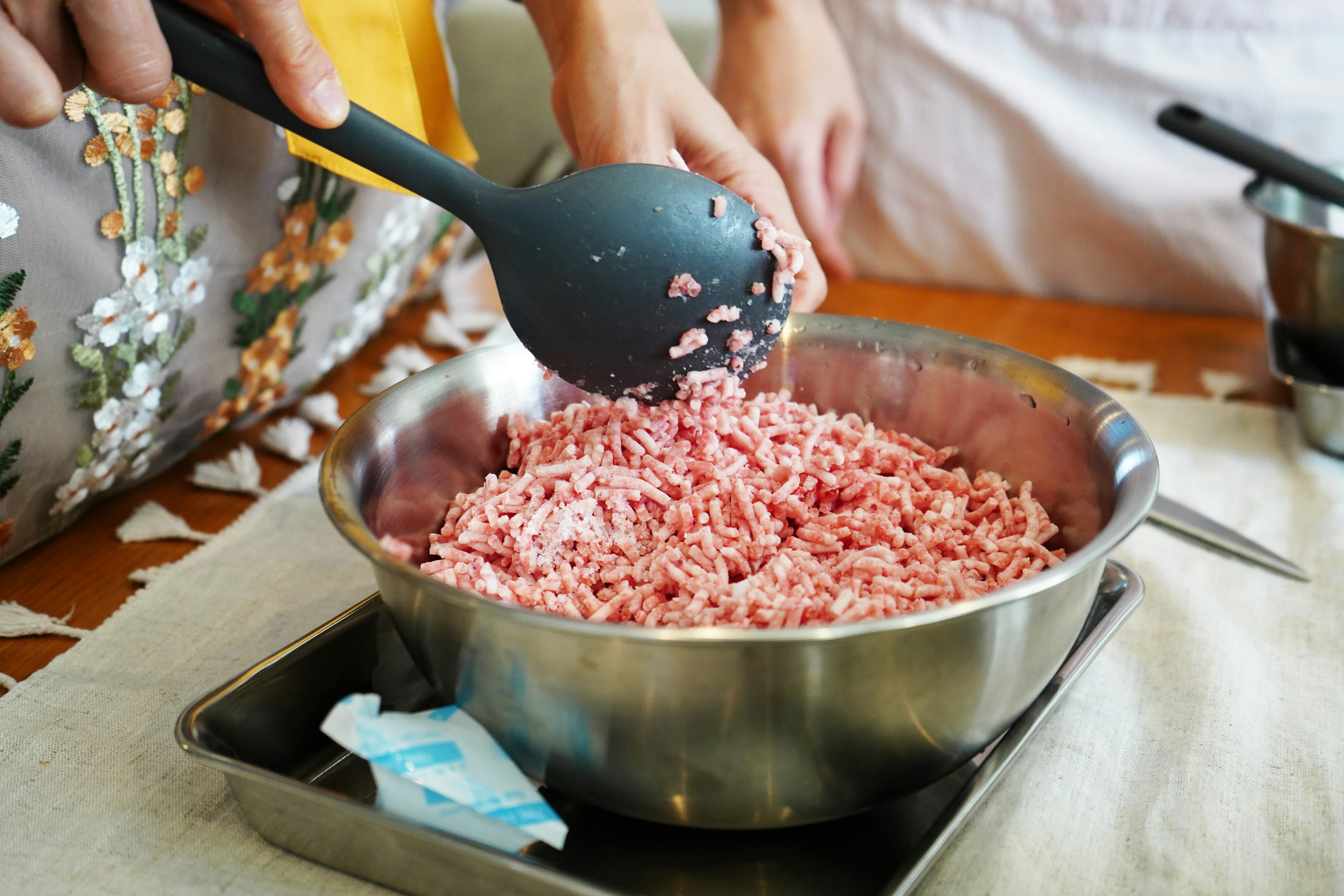 手在金属碗中搅拌碎肉的特写