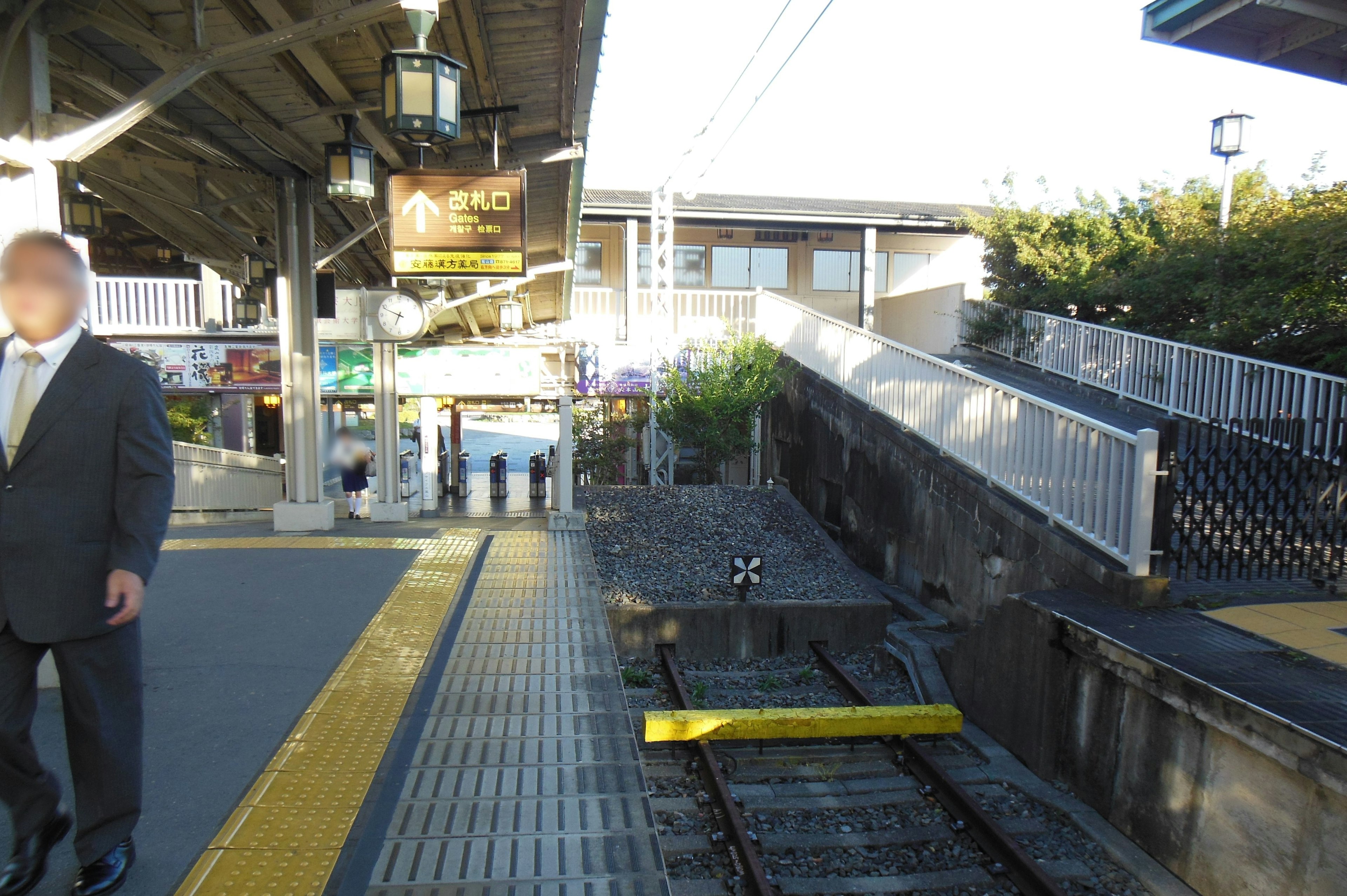 駅のプラットフォームに立つビジネスマンと周囲の風景