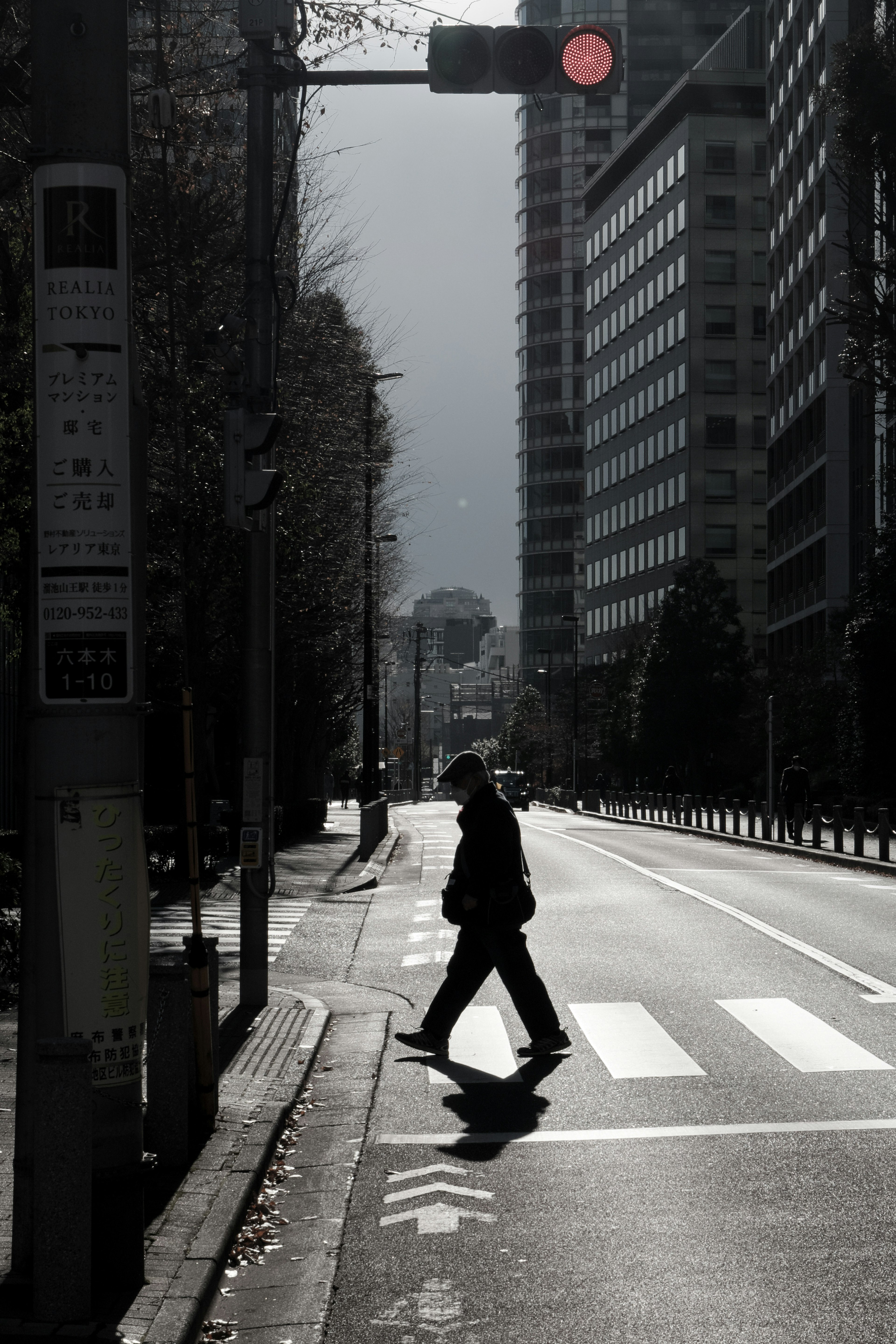 Silhouette einer Person, die eine Straße an einem Zebrastreifen mit rotem Ampelsignal überquert