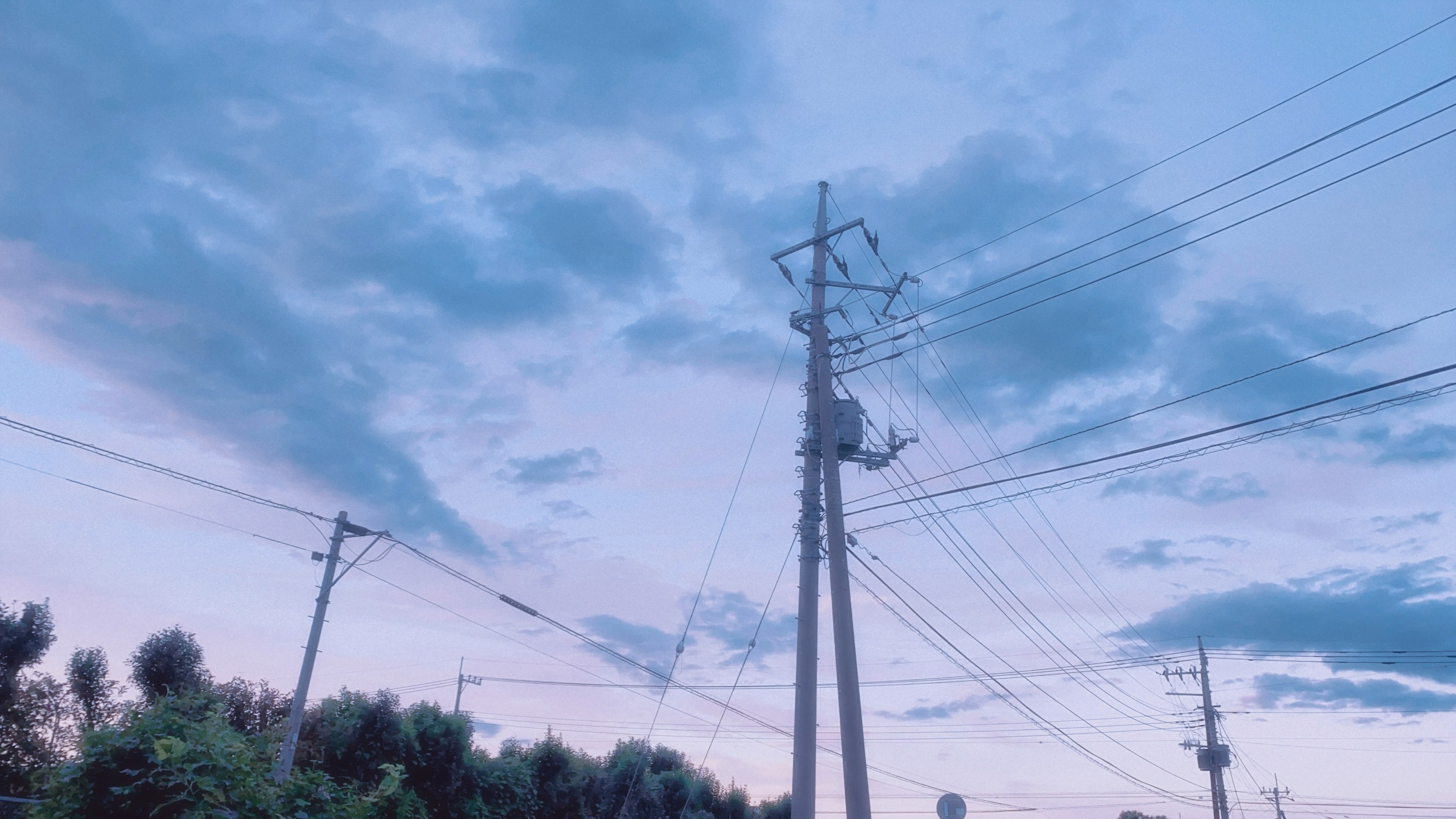 青い空と雲に囲まれた電柱と電線の風景