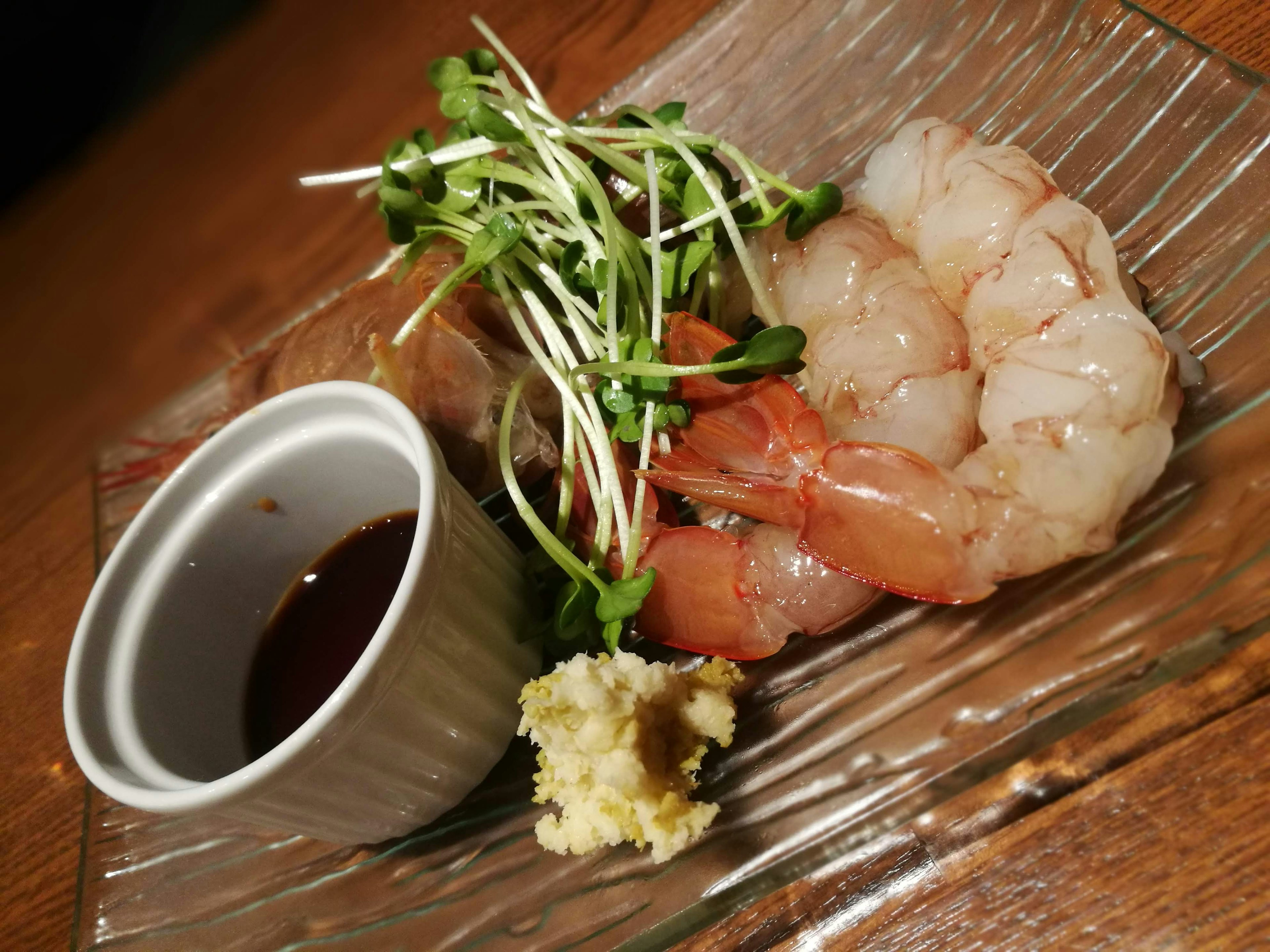 Fresh shrimp with ginger and vegetable garnish on a plate