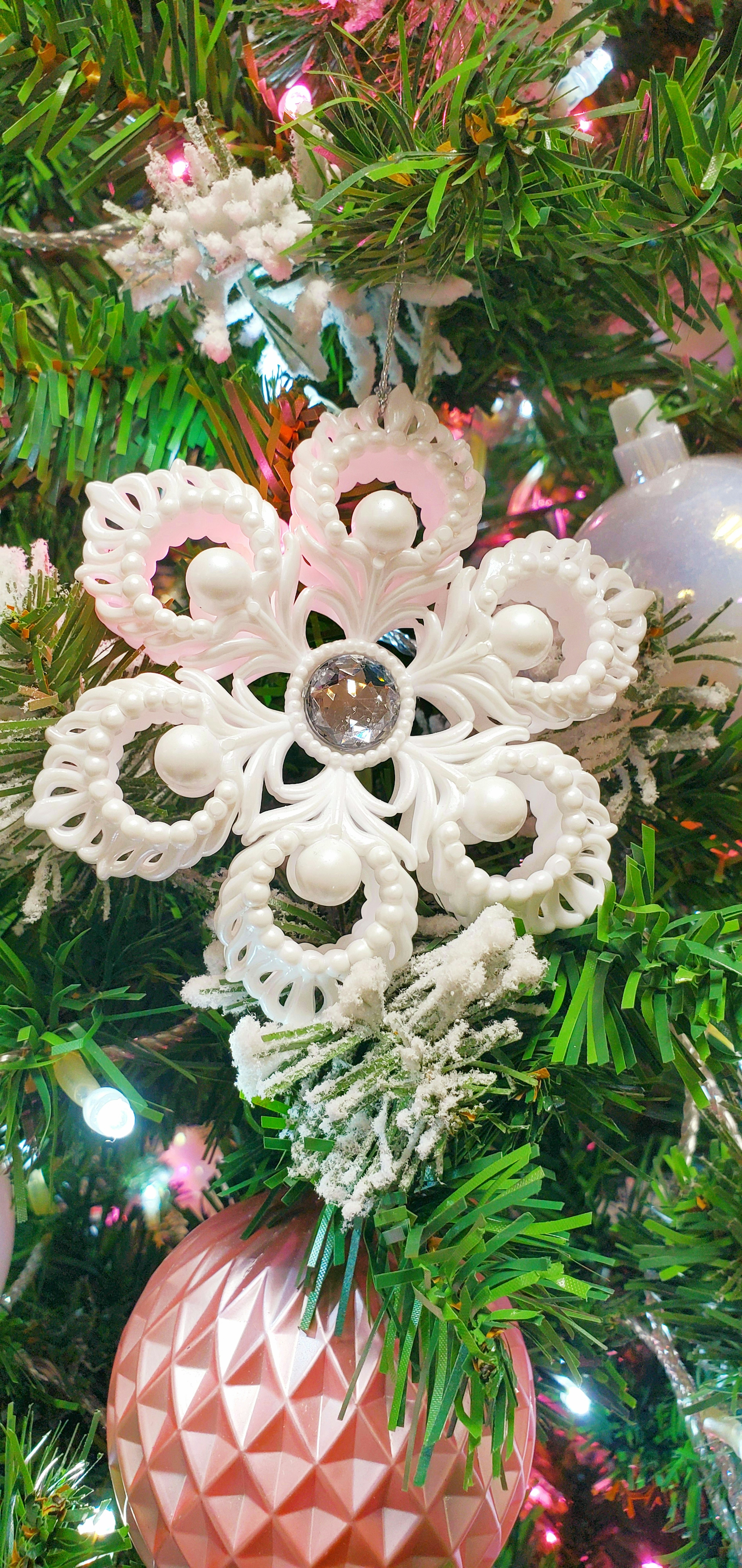 Decorazione a forma di fiocco di neve bianco su un albero di Natale con decorazioni rosa