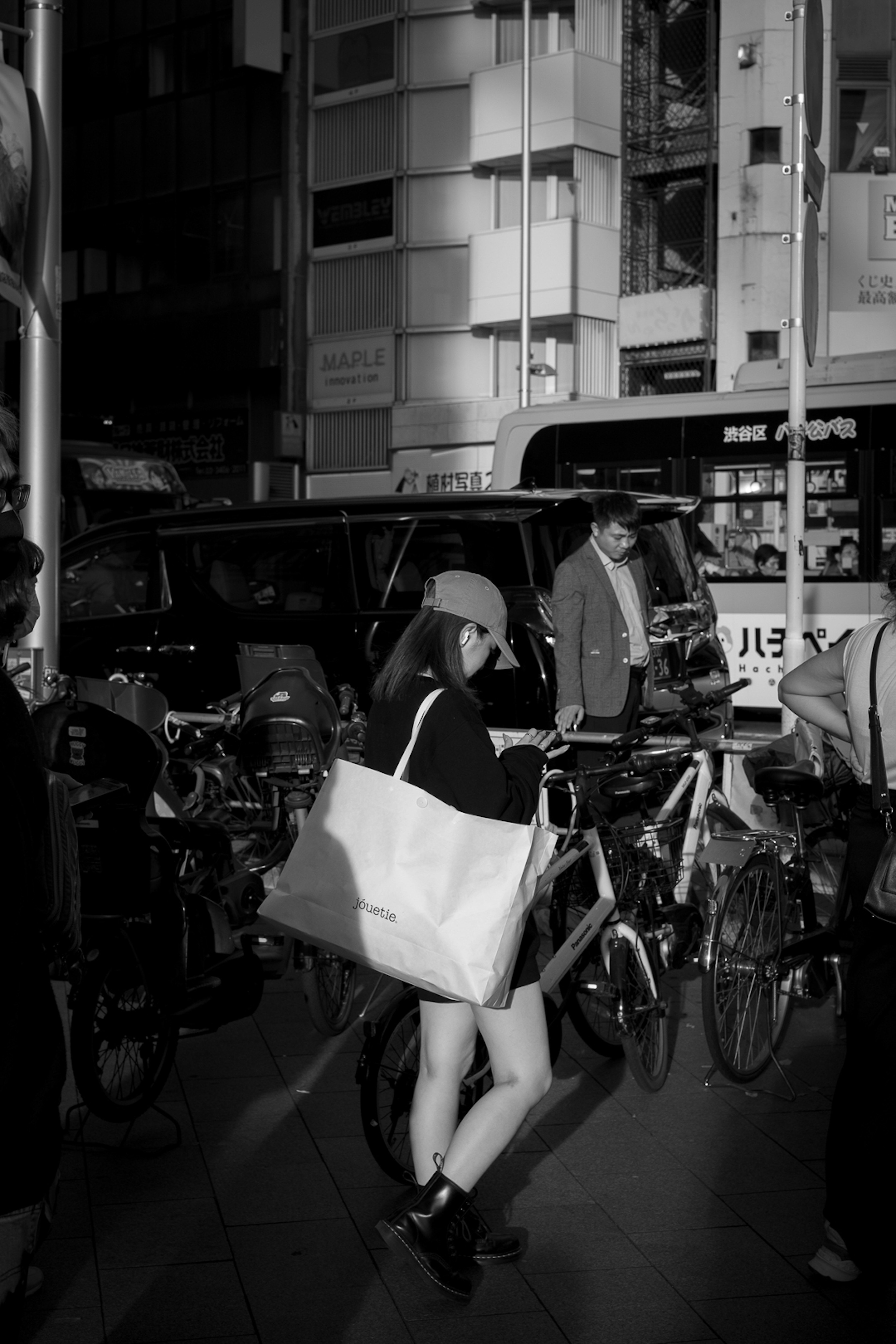 Una mujer con una bolsa blanca caminando entre bicicletas en una calle de la ciudad