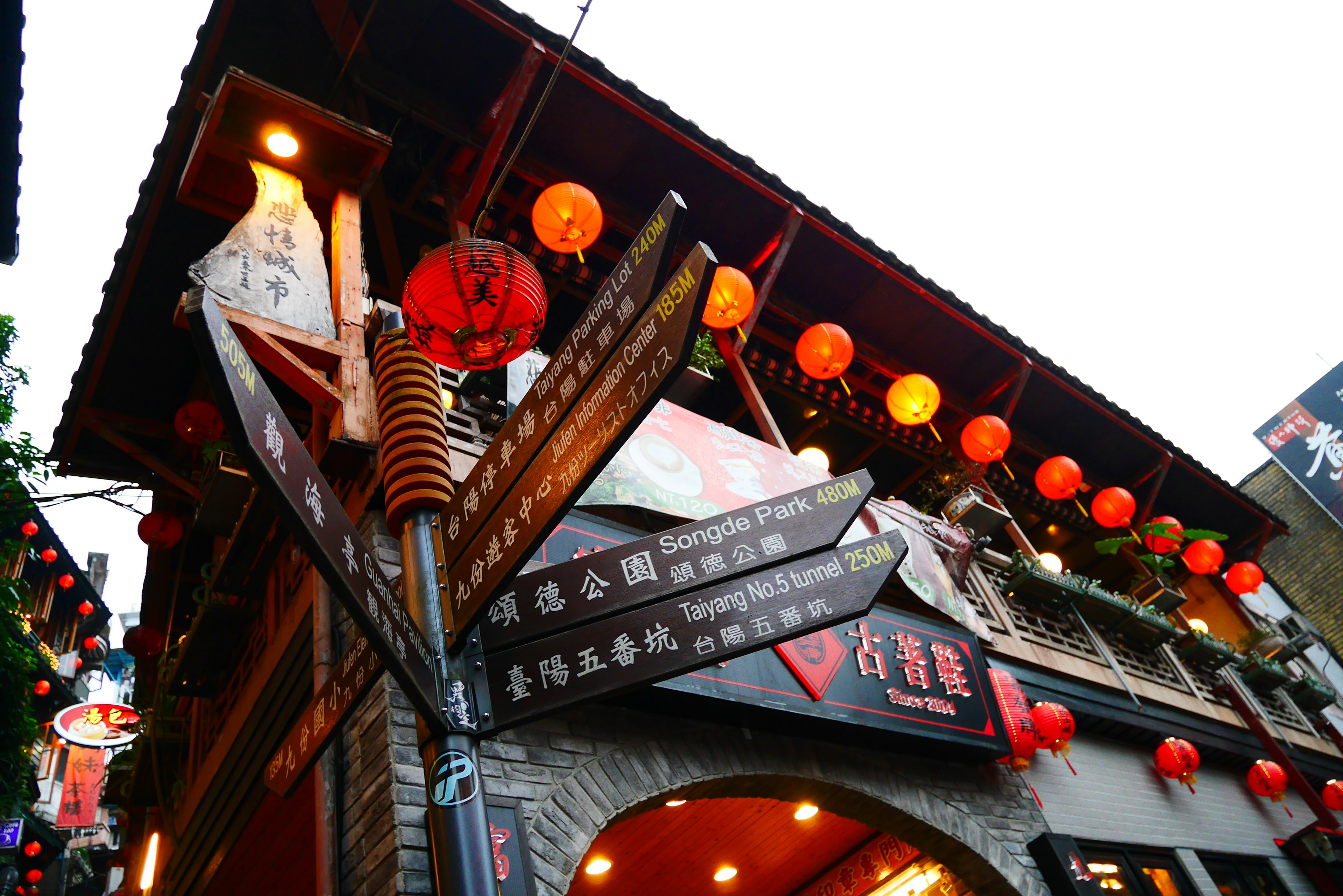 Exterior de un edificio tradicional decorado con faroles rojos y señales multilingües