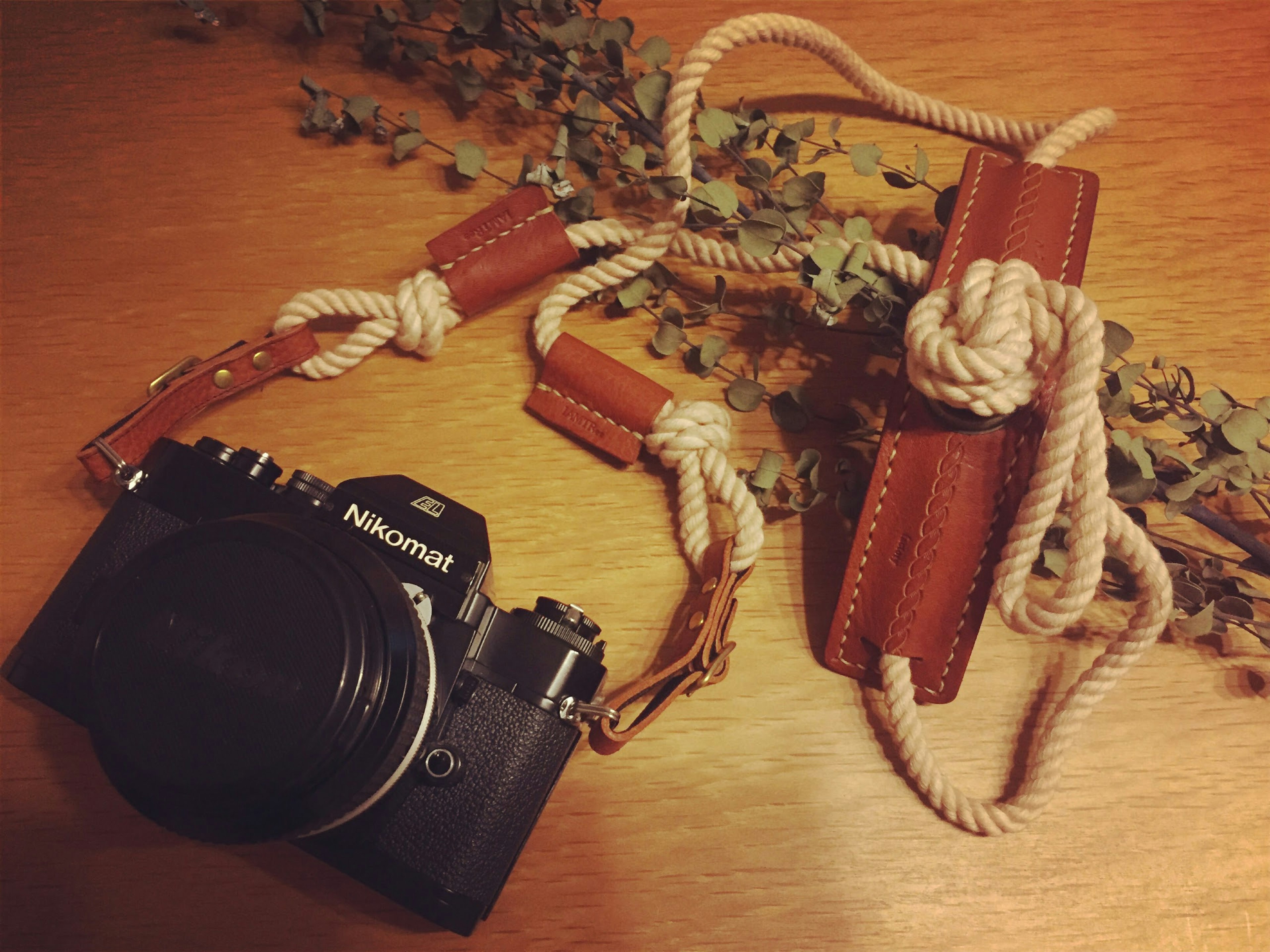 Appareil photo avec sangle en cuir posé sur une table en bois