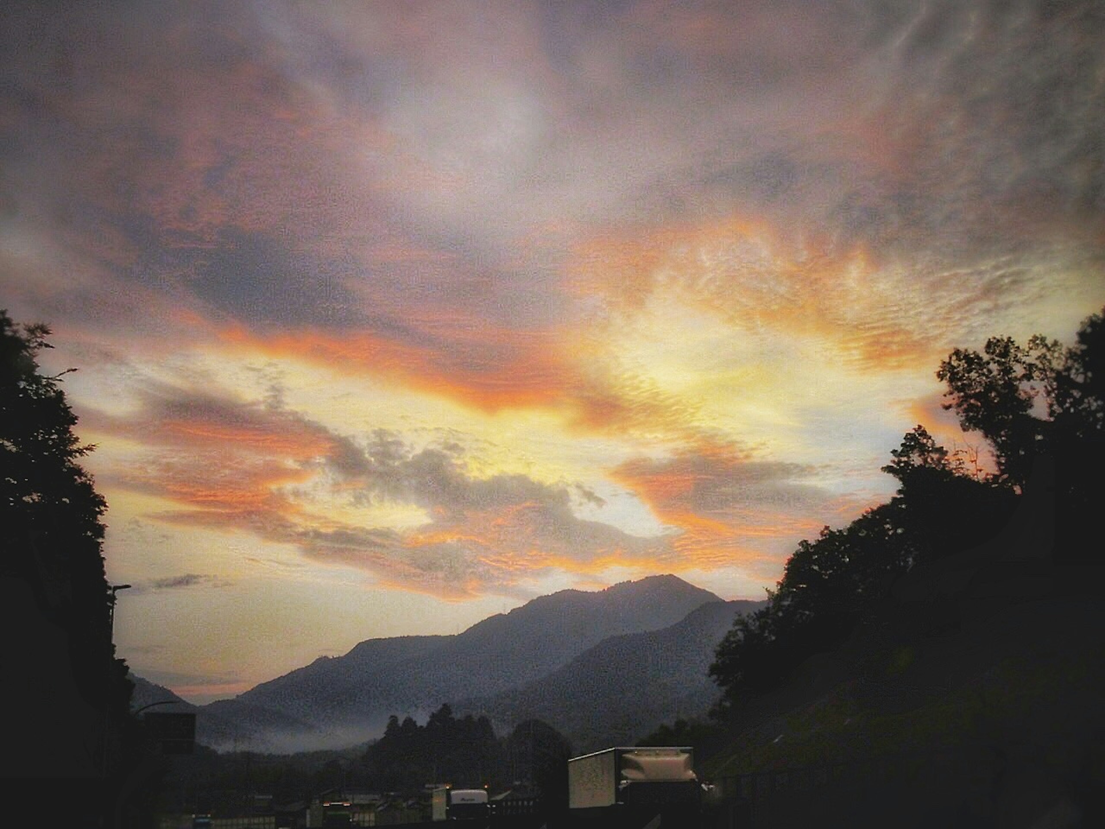 Vista escénica de un cielo al atardecer con montañas y camiones visibles