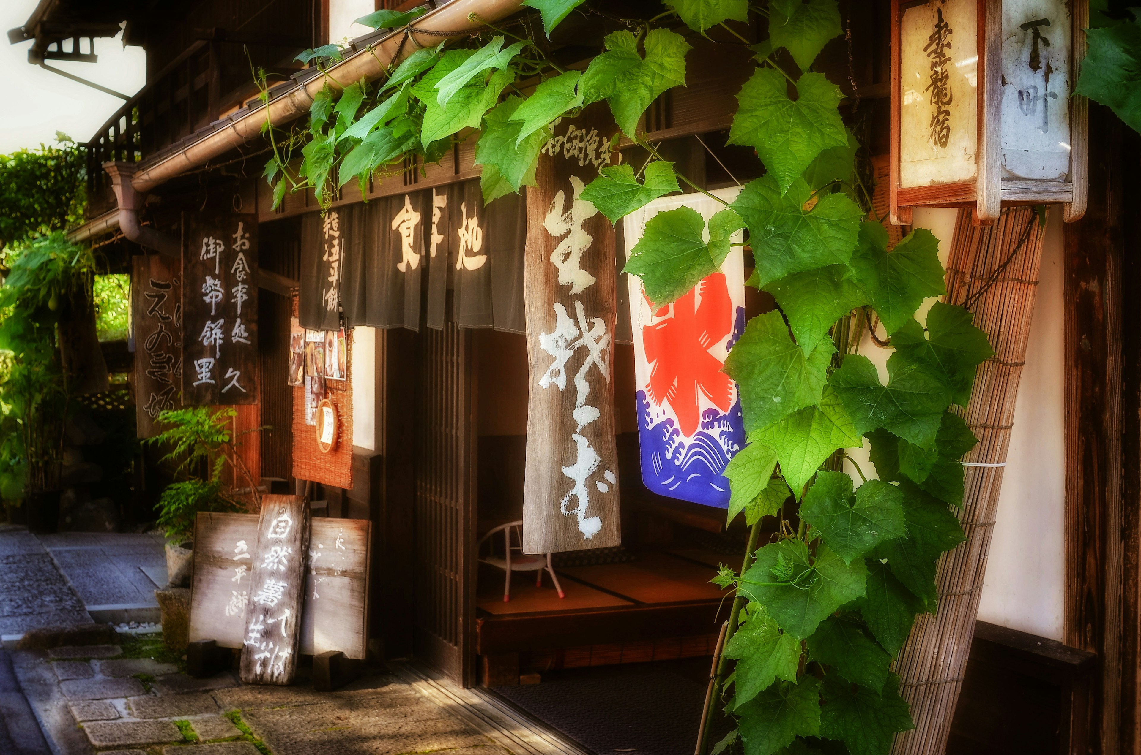 Exterior de una tienda japonesa tradicional cubierta de hojas verdes con una bandera y letreros