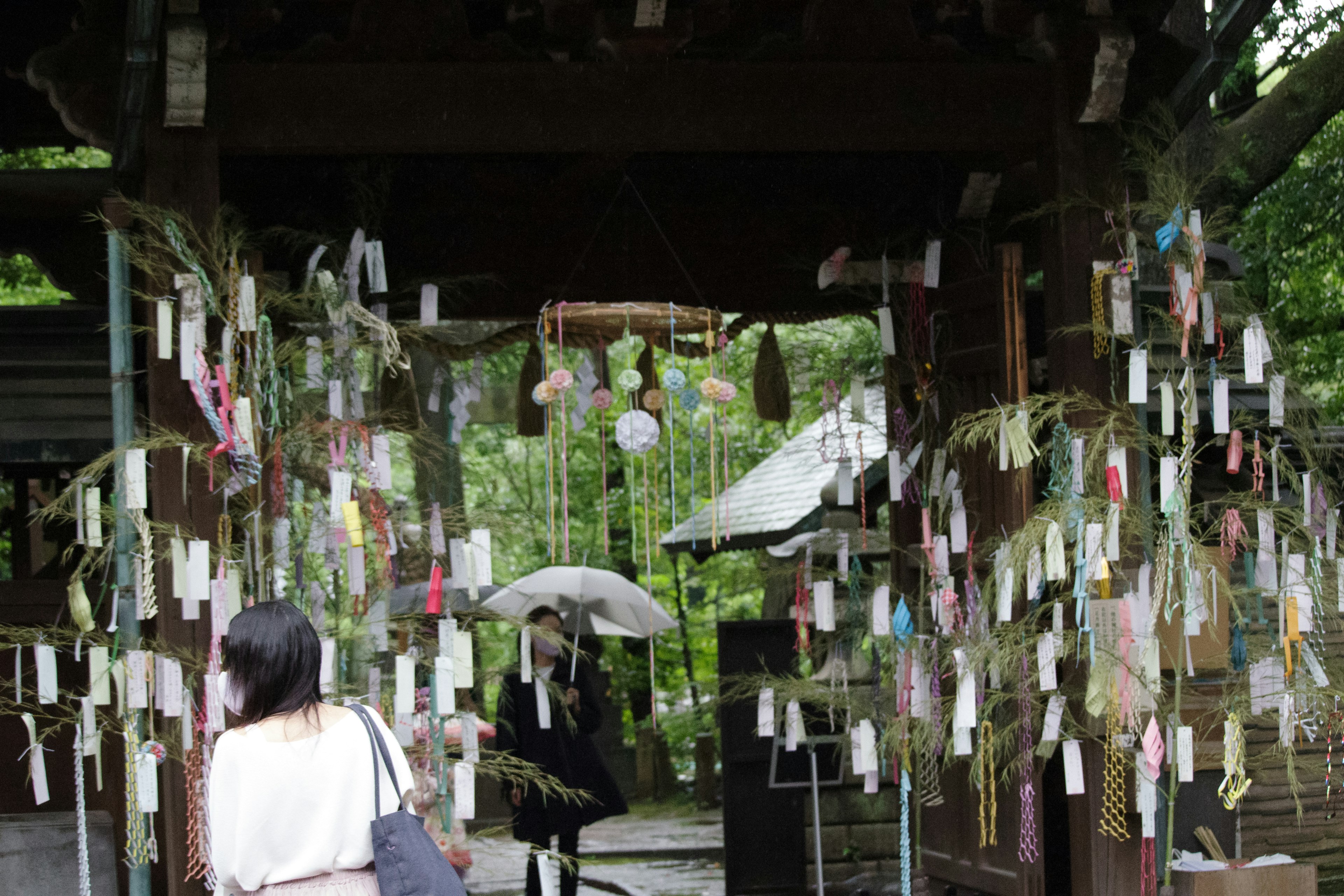 一位女性站在裝飾著彩色紙條的神社門前