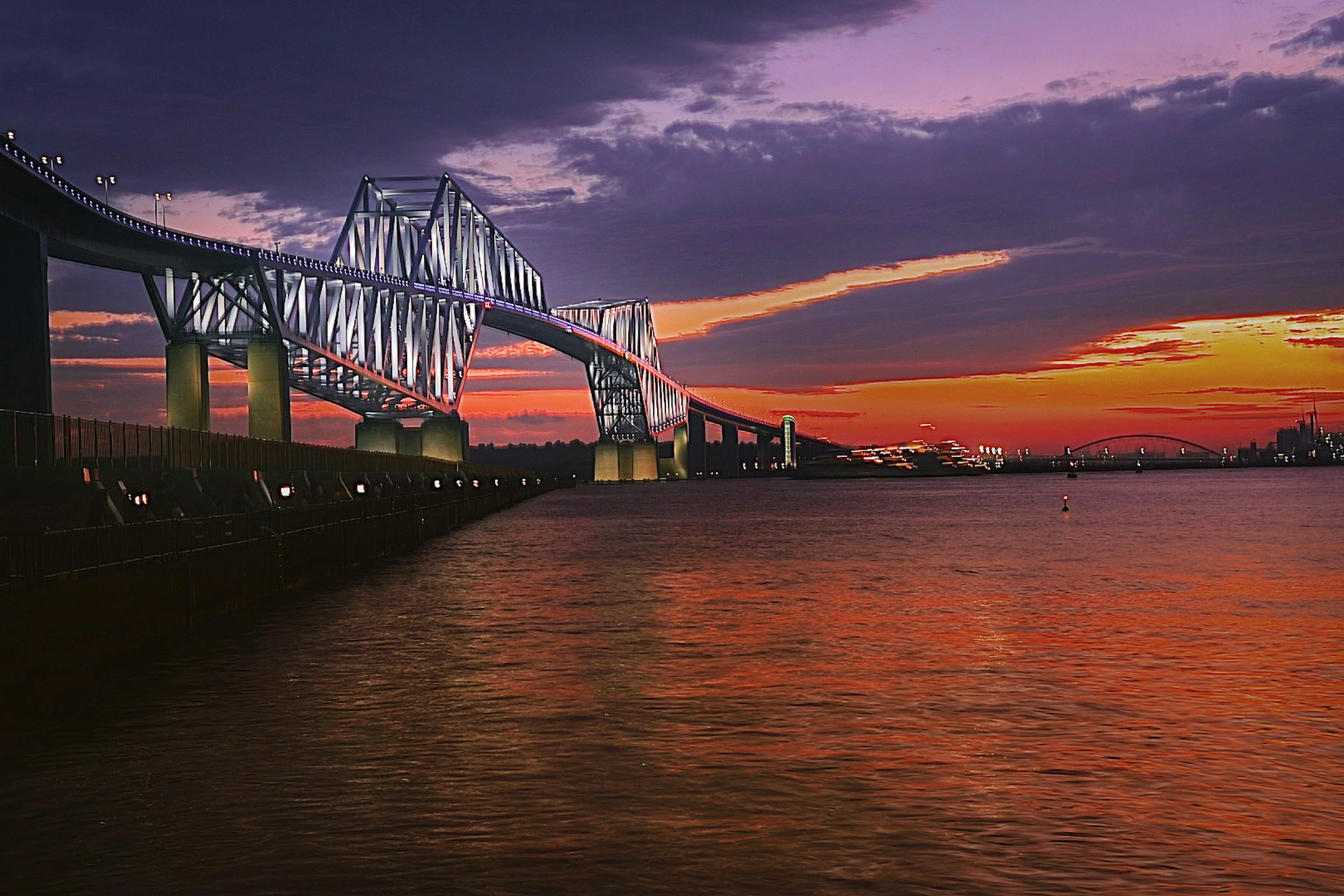 Brücke, die vom Sonnenuntergang über ruhigem Wasser beleuchtet wird