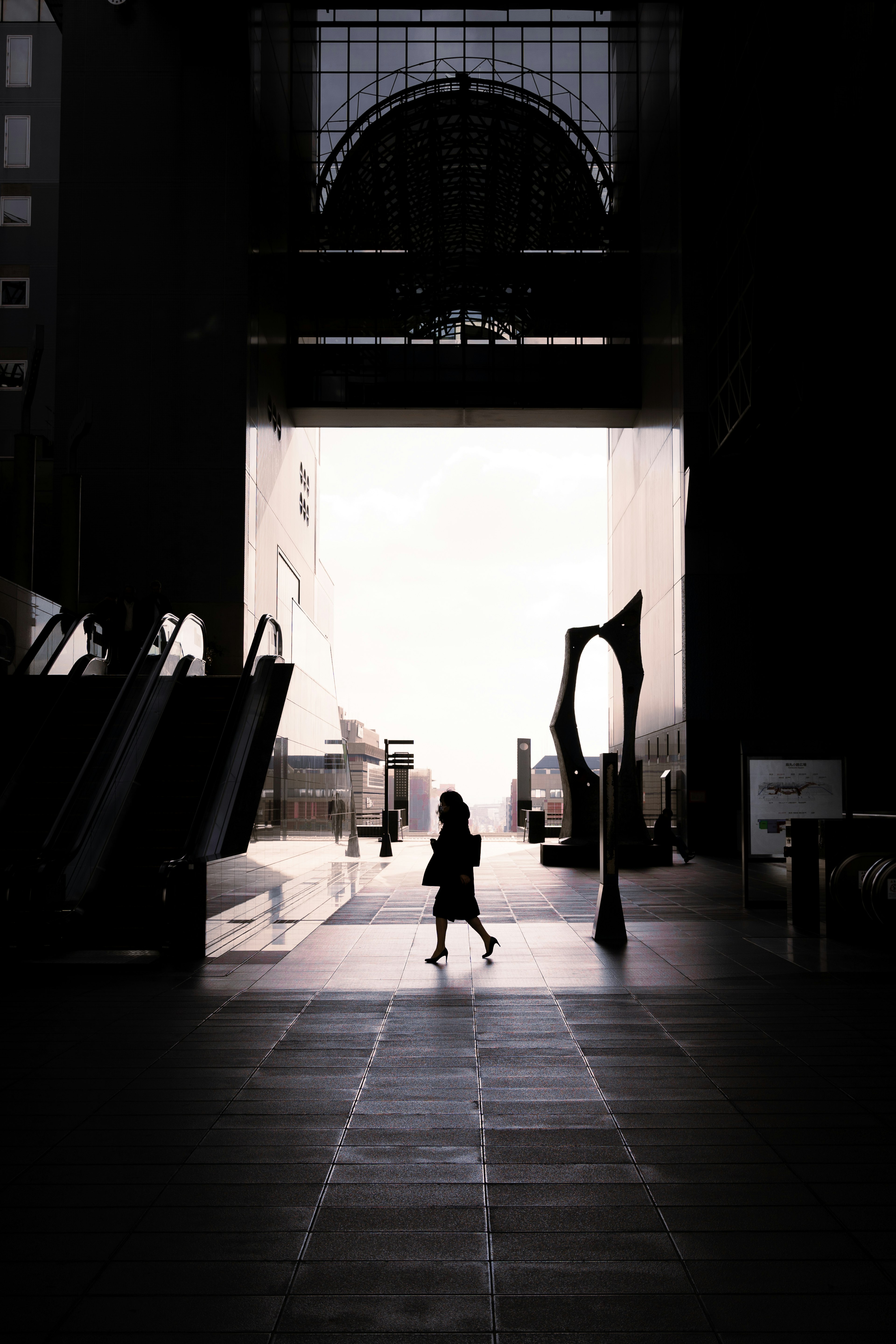 Silhouette of a child walking in a large archway within a dark space