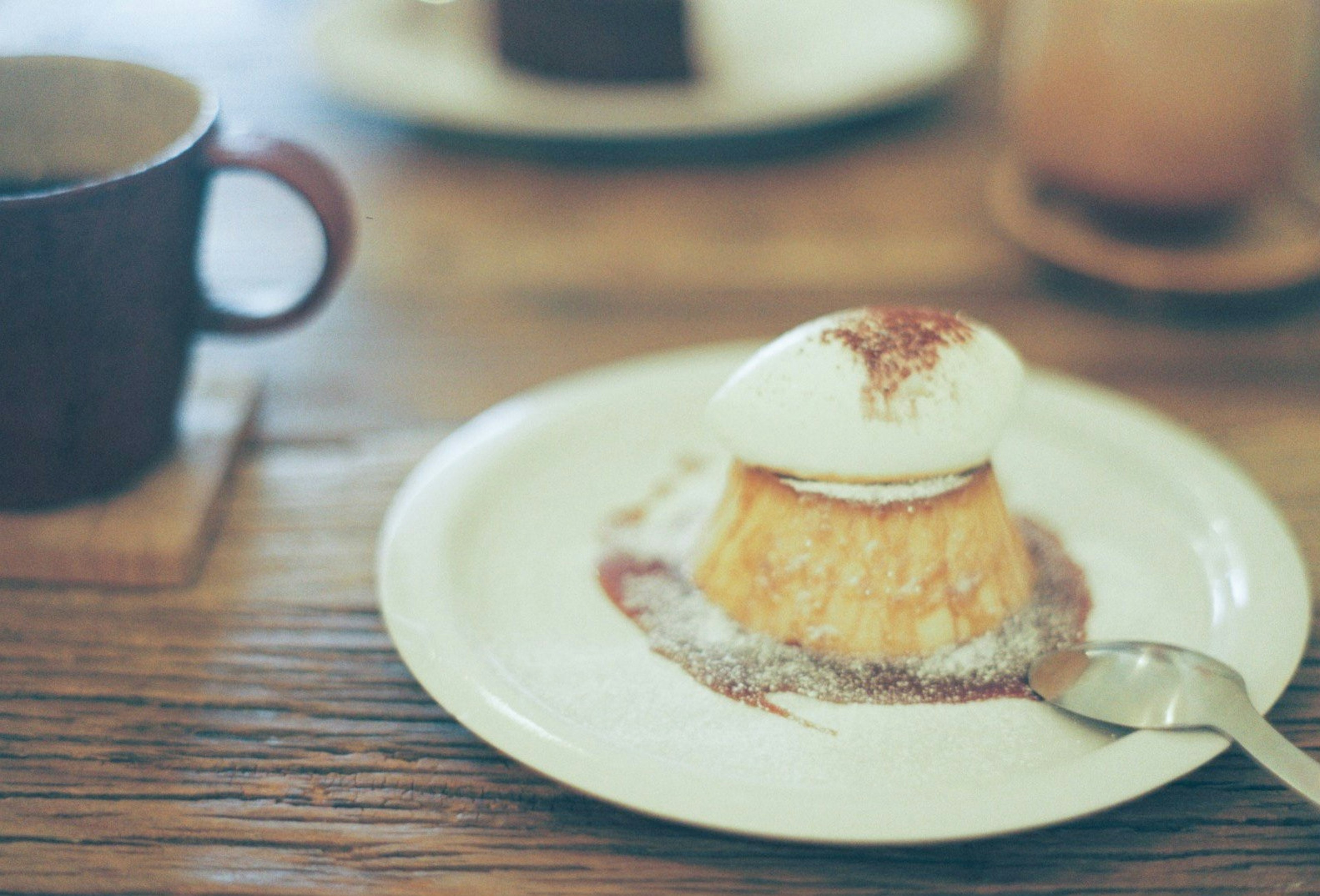 Dessert guarnito con panna e zucchero a velo con una tazza di caffè sul tavolo