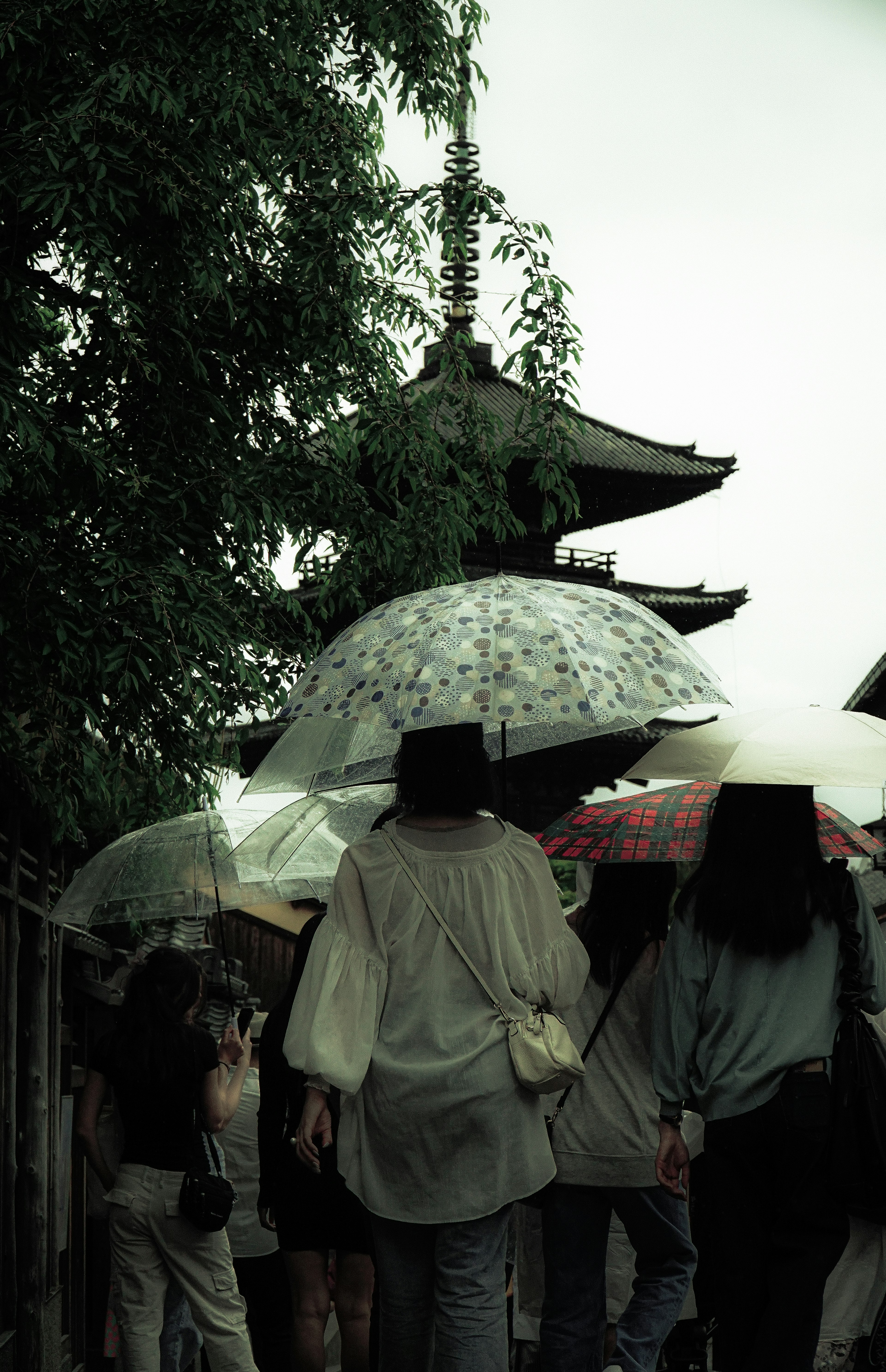 Des gens marchant avec des parapluies près d'un ancien temple