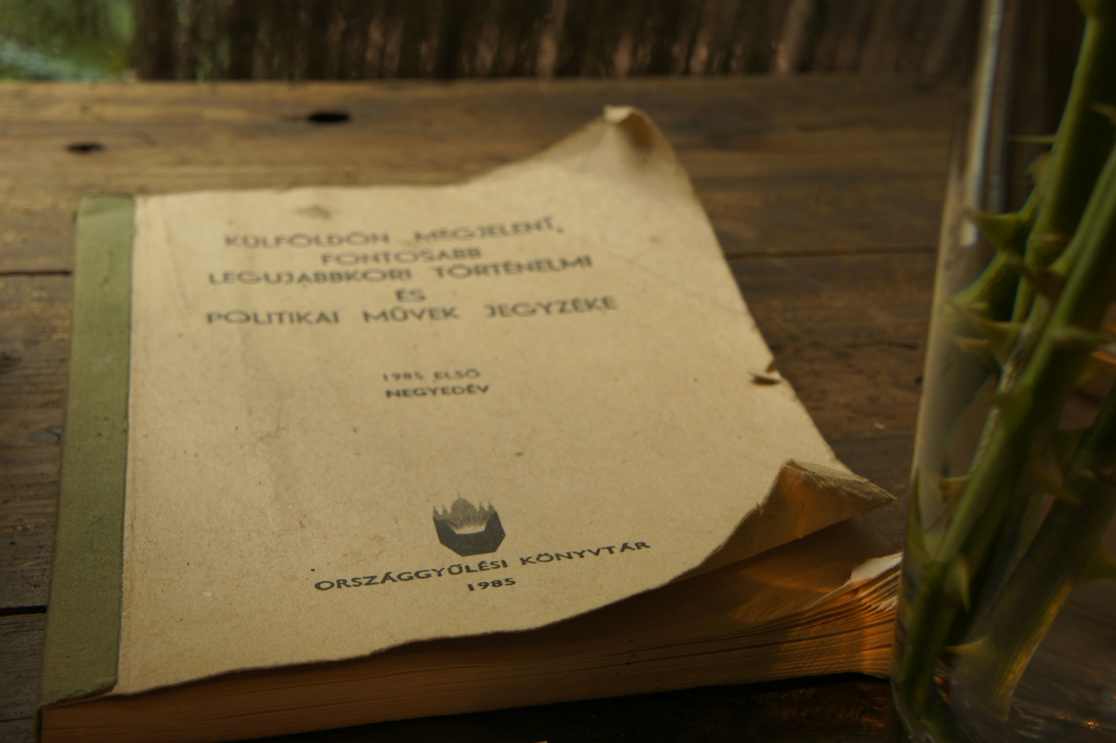 An old book resting on a wooden table with a slightly turned page