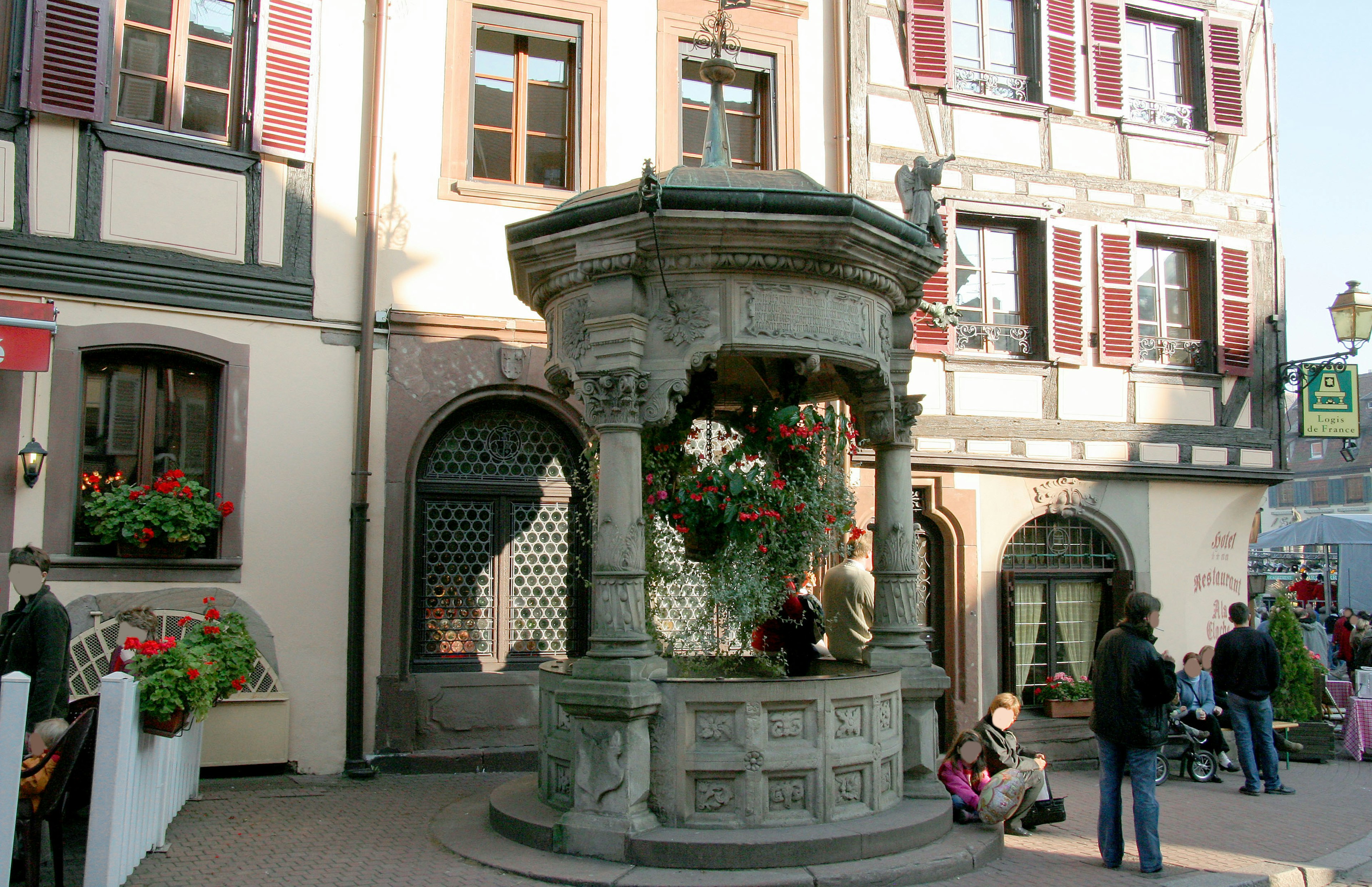 Ein schöner Steinbrunnen umgeben von historischen Gebäuden und Blumen