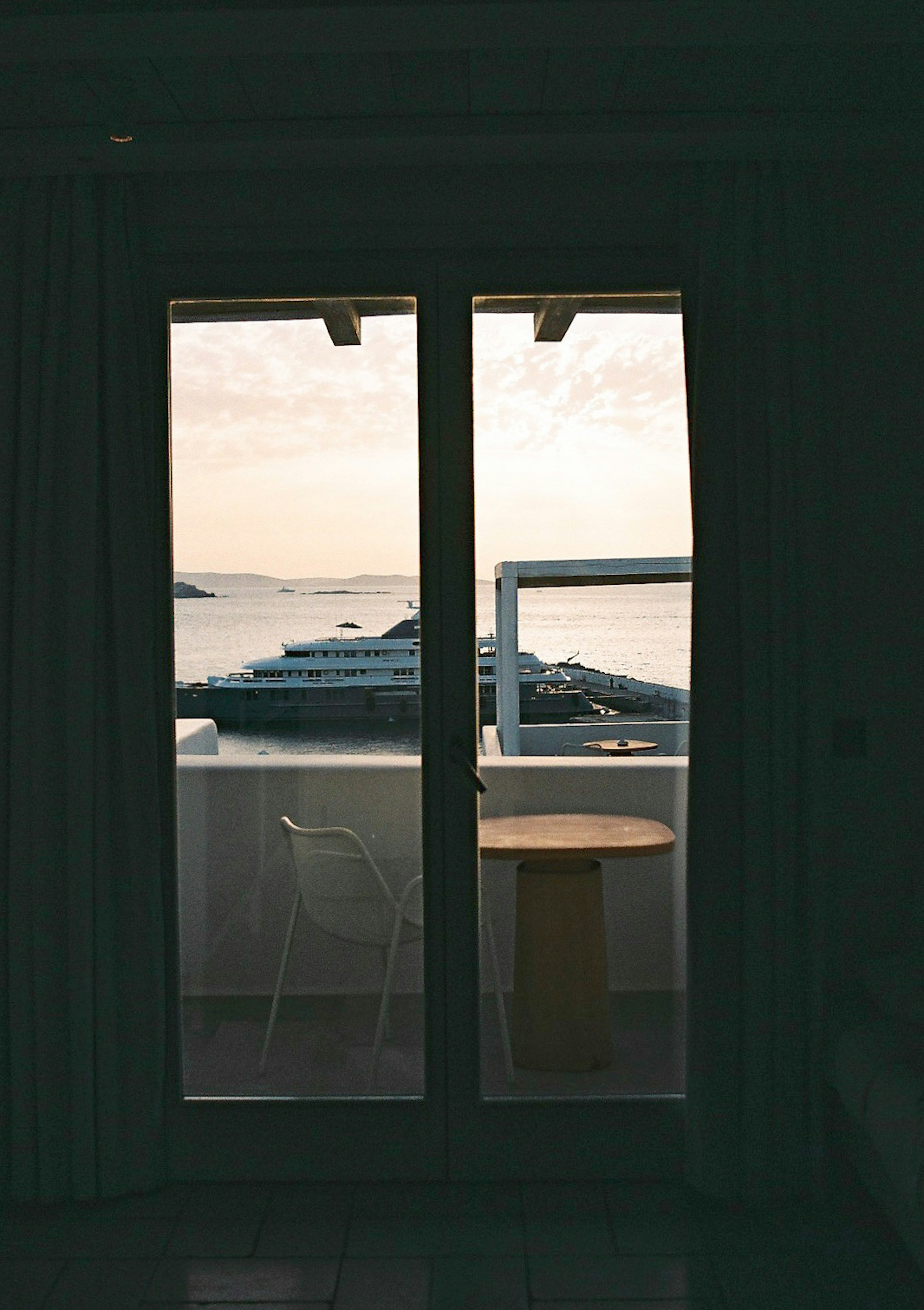 Vista interior de una habitación con puerta de balcón y mesa con vista al mar