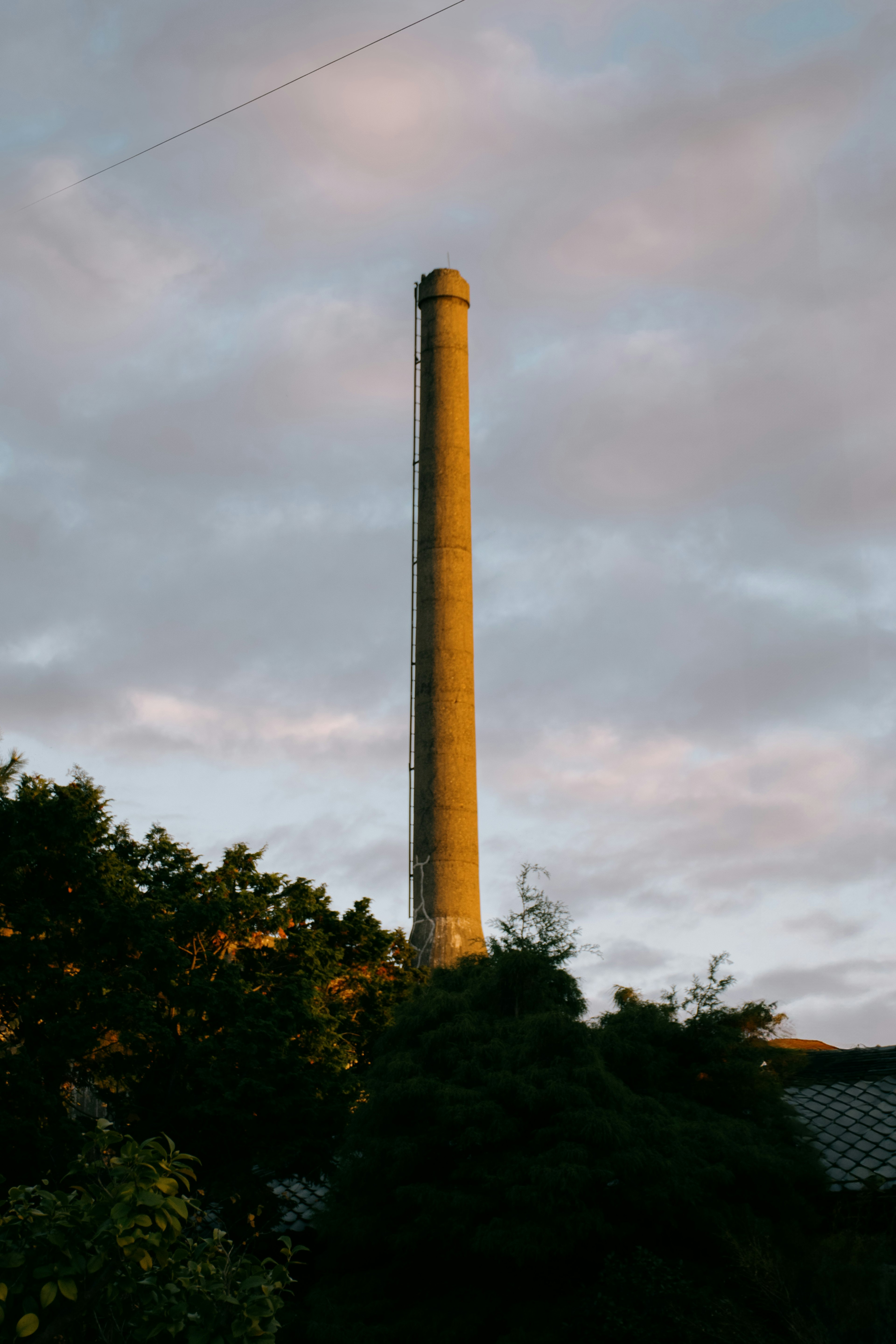 A tall smokestack illuminated by sunset