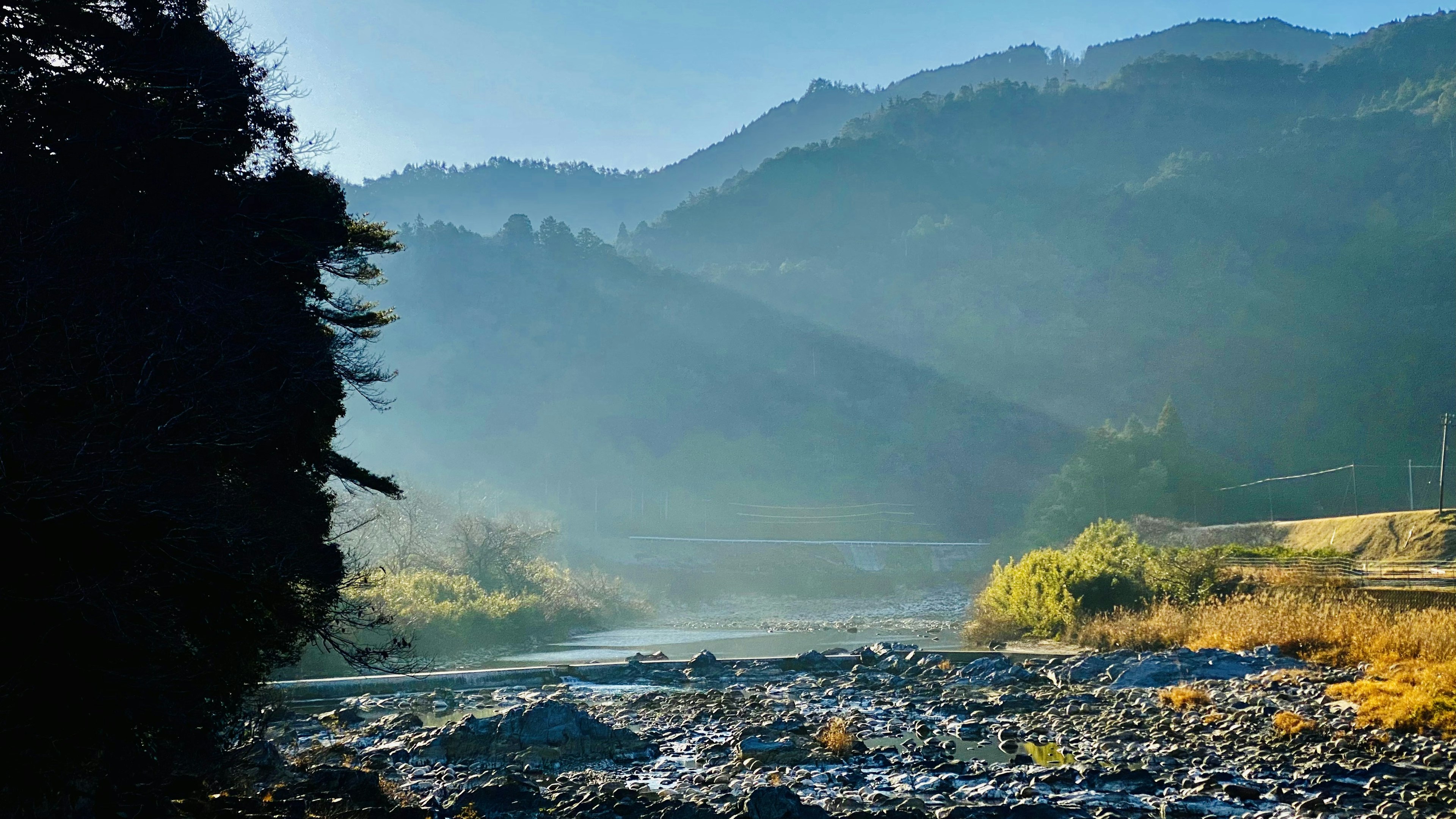 Paesaggio sereno di fiume e montagne con nebbia