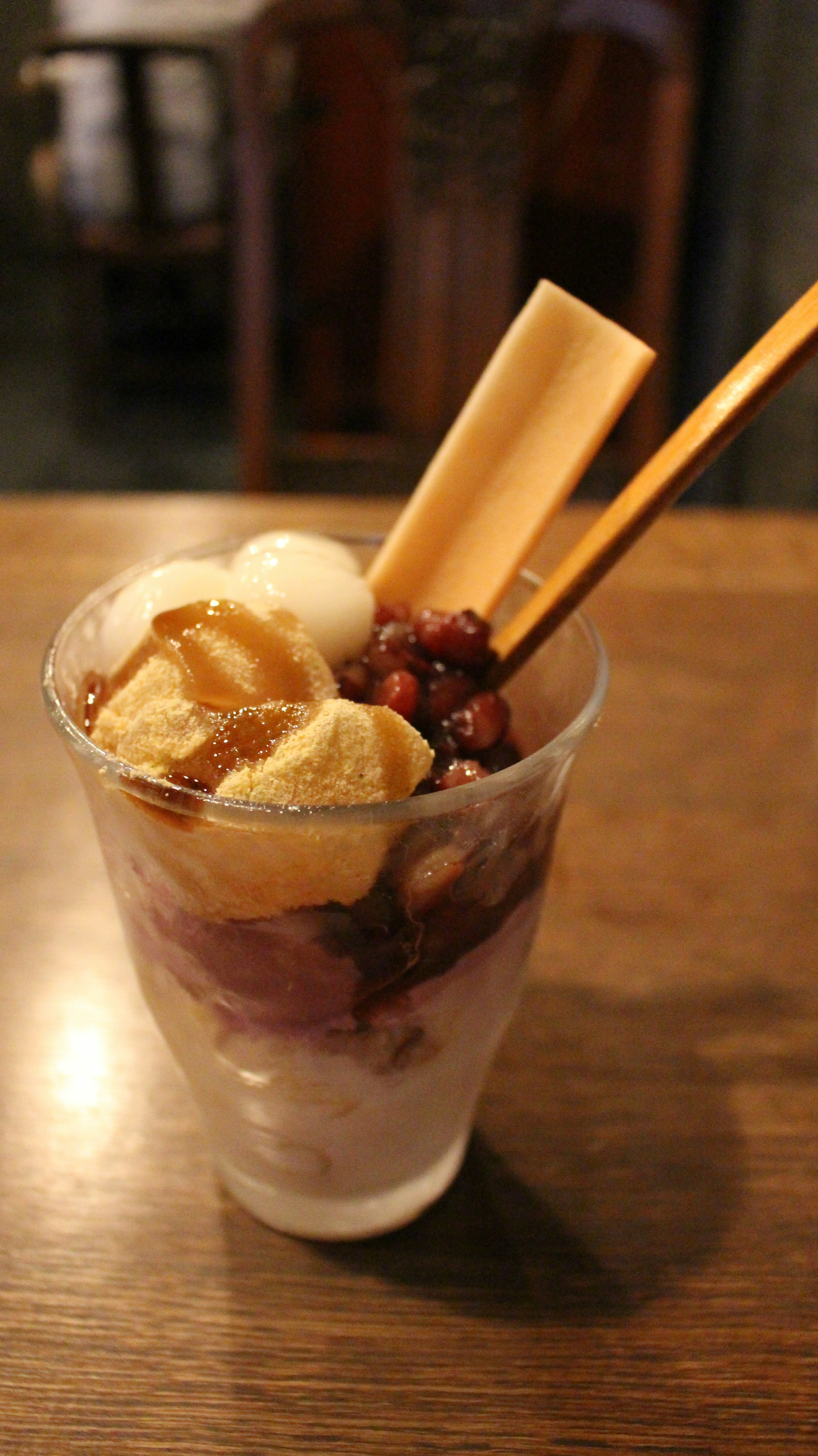 Copa de postre con helado cubierto de pasta de frijoles rojos plátano y palitos de galleta