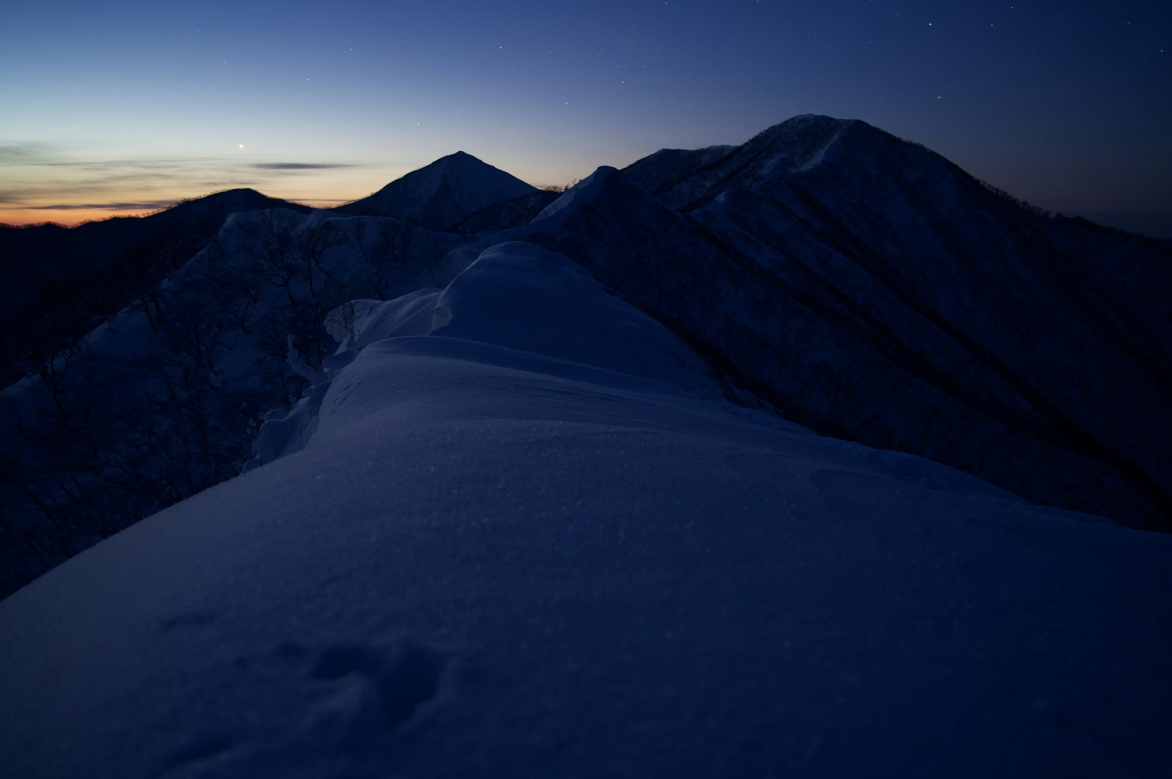 雪に覆われた山々の夜景と薄明かり