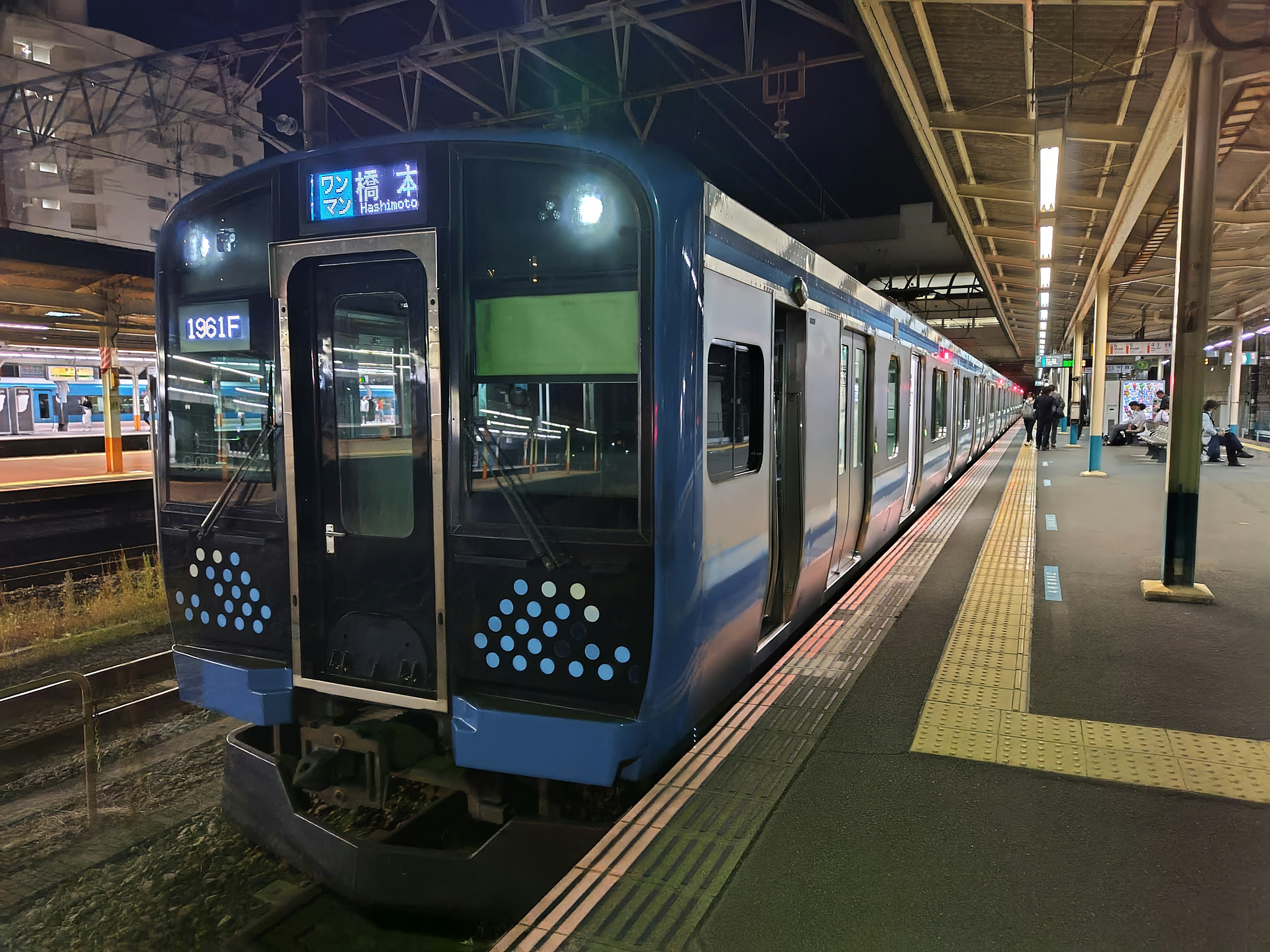 Kereta biru yang berhenti di stasiun pada malam hari dengan lampu peron