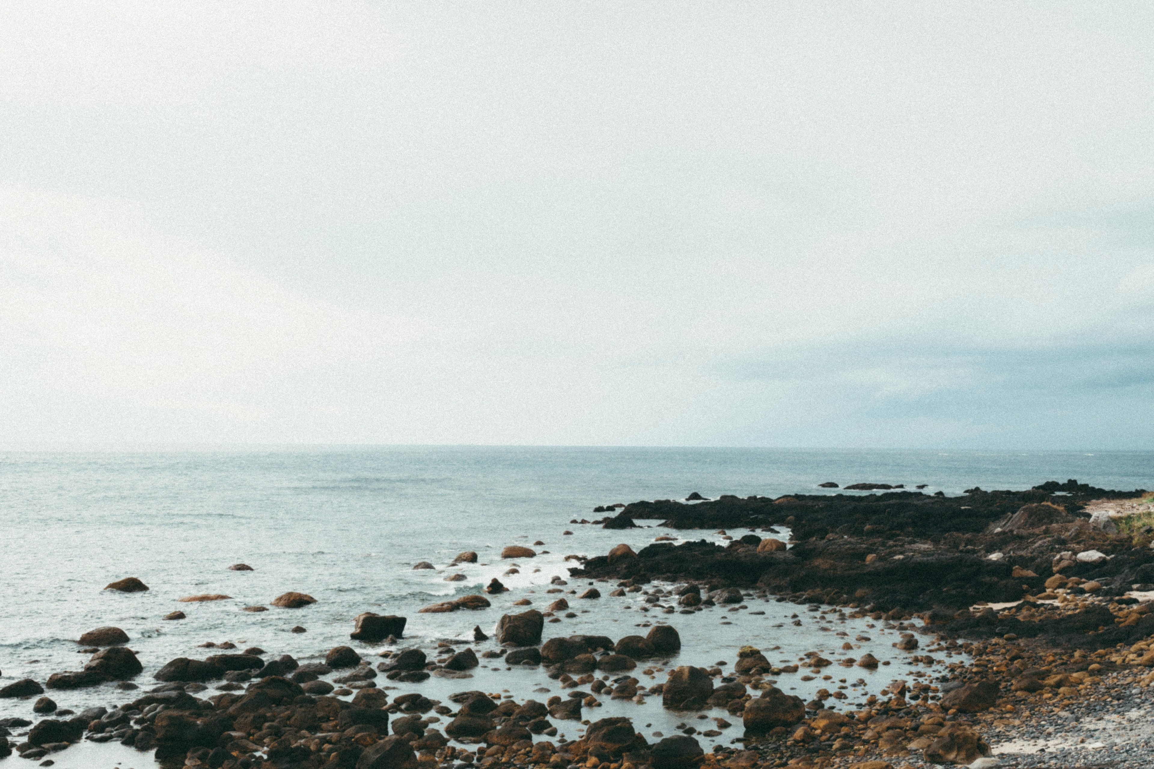 Laut tenang dan garis pantai berbatu di bawah langit mendung