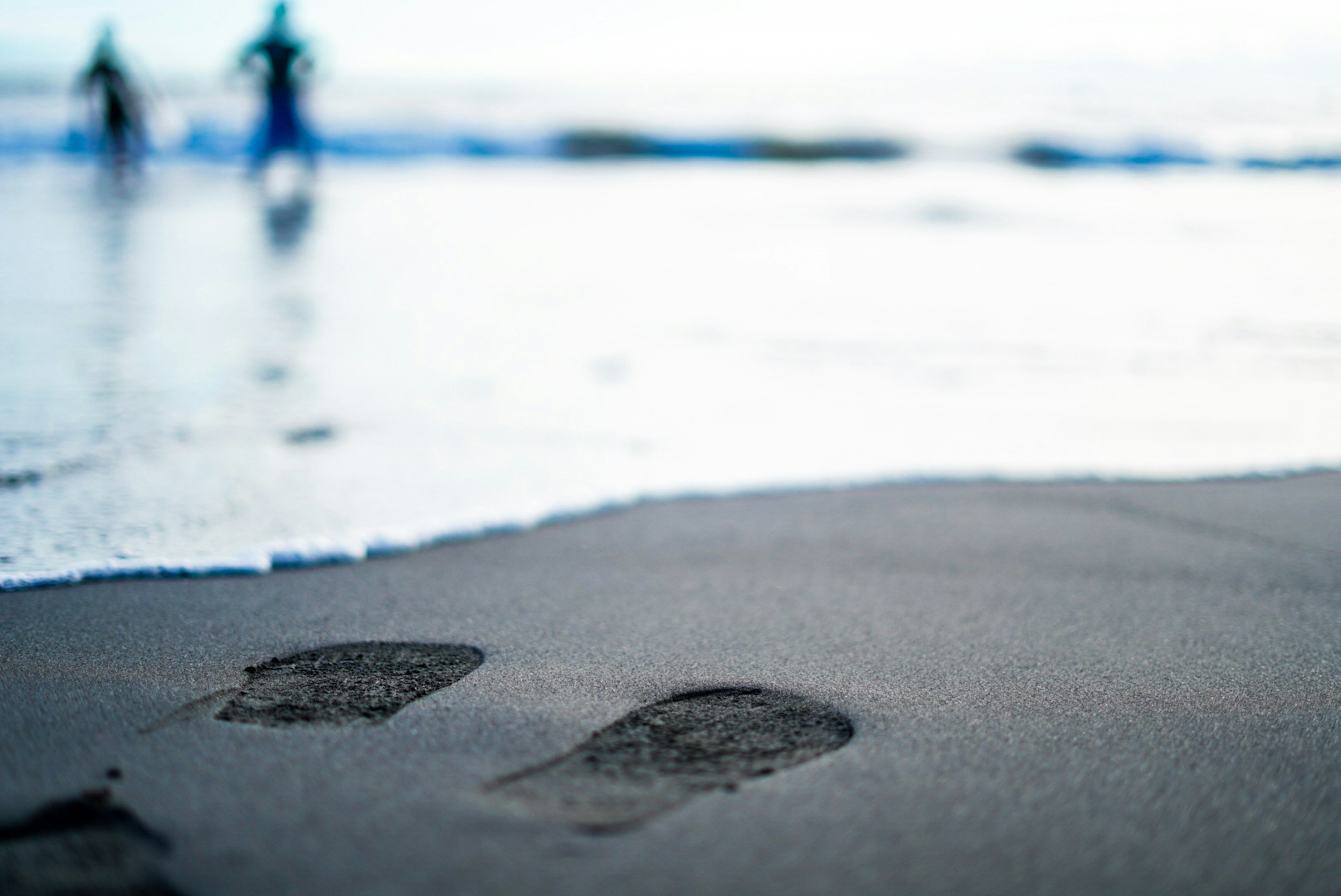 Fußabdrücke im Sand mit Wellen im Hintergrund