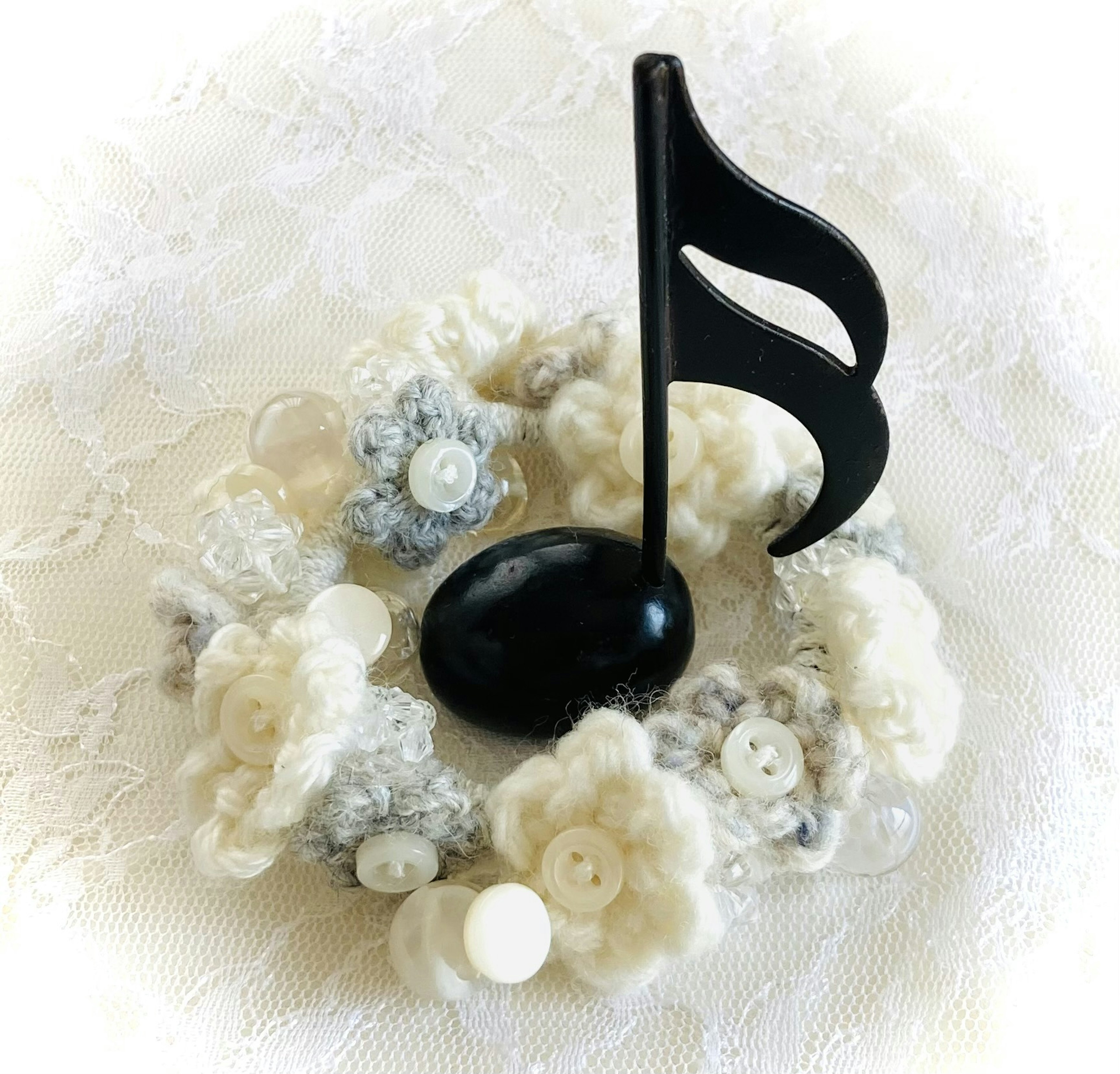 A black musical note on a floral arrangement of white and gray flowers