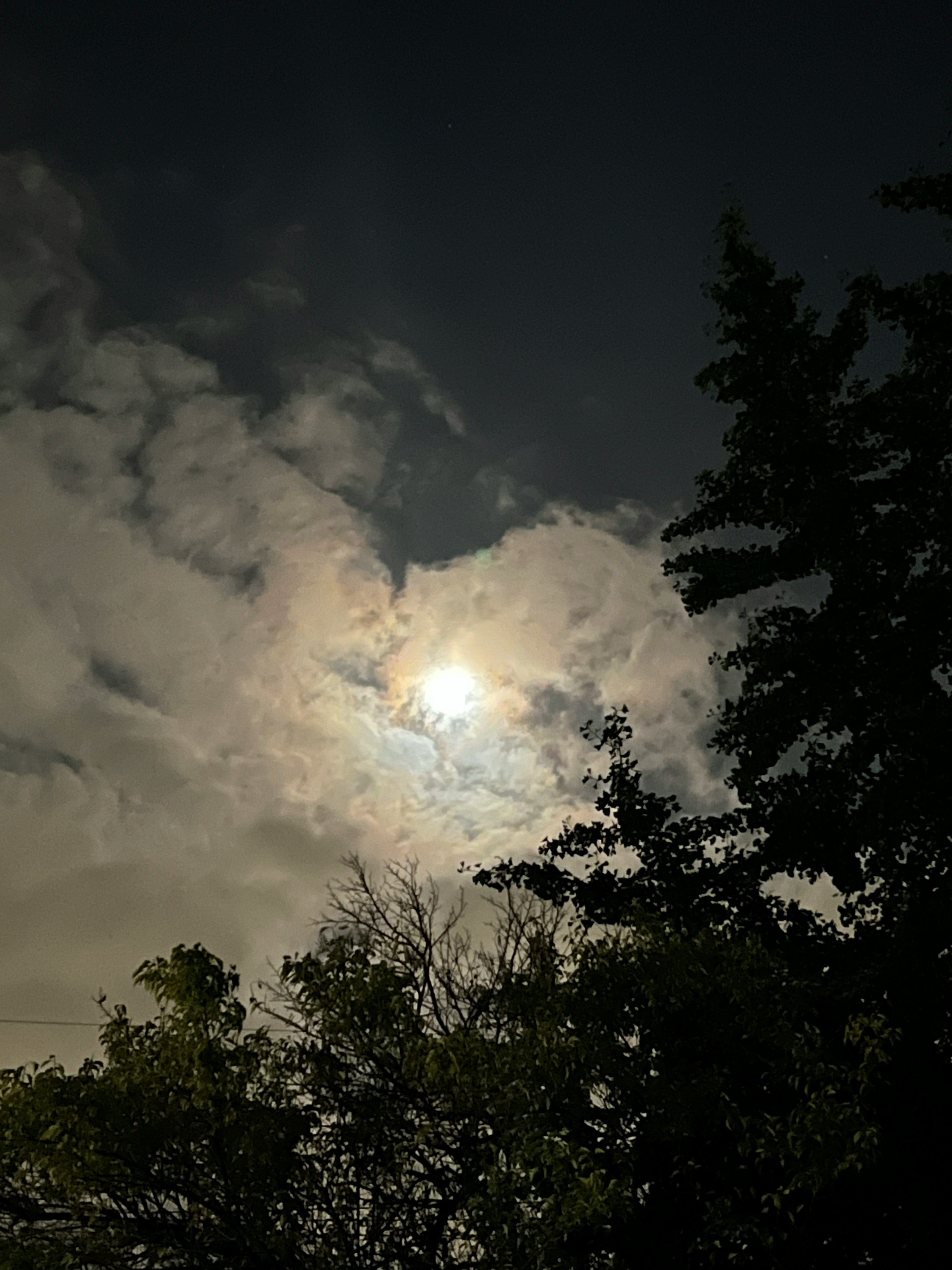 月明かりが雲の間から差し込む夜空の風景