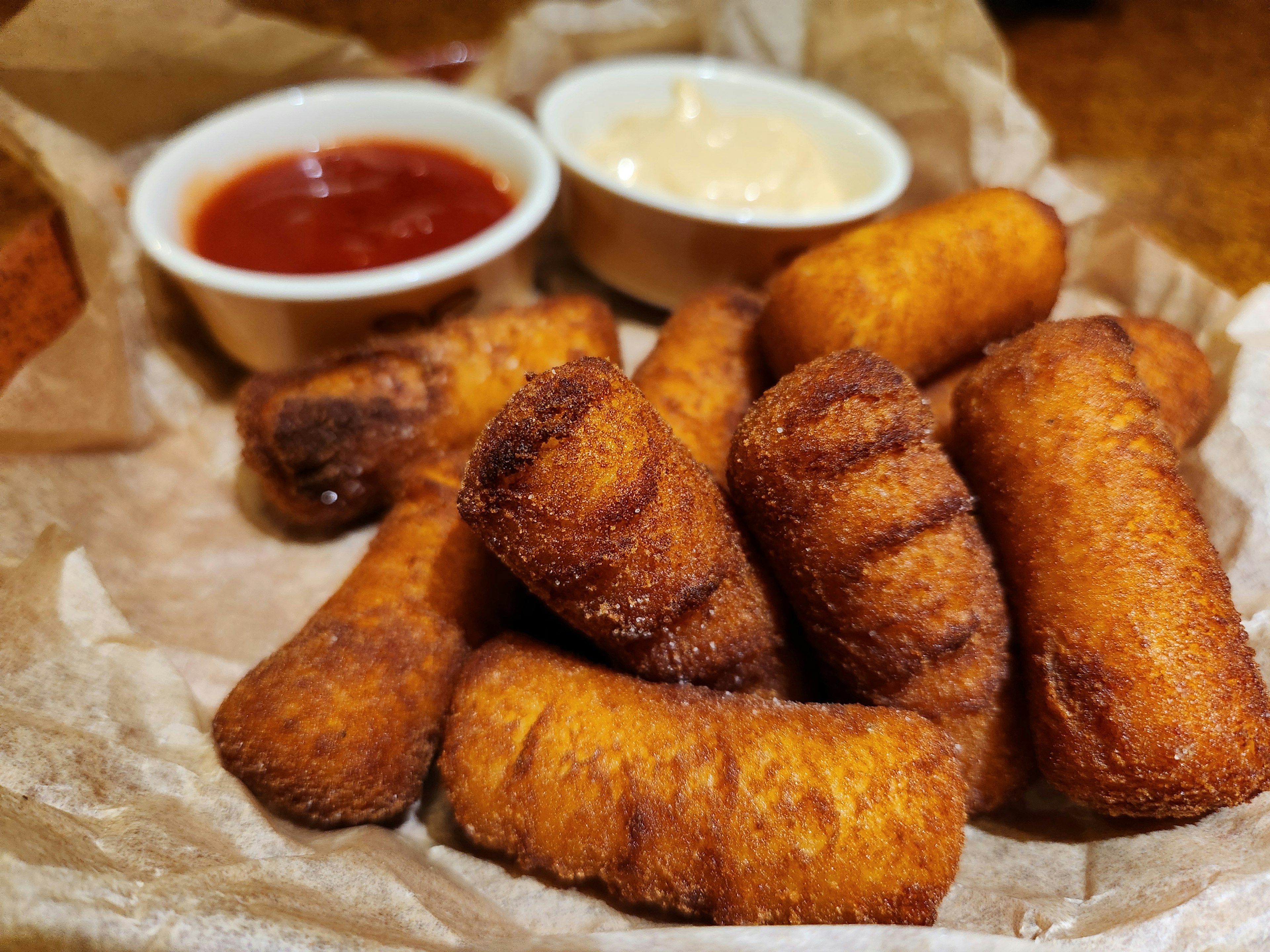 A basket of fried snacks served with ketchup and mayonnaise dips