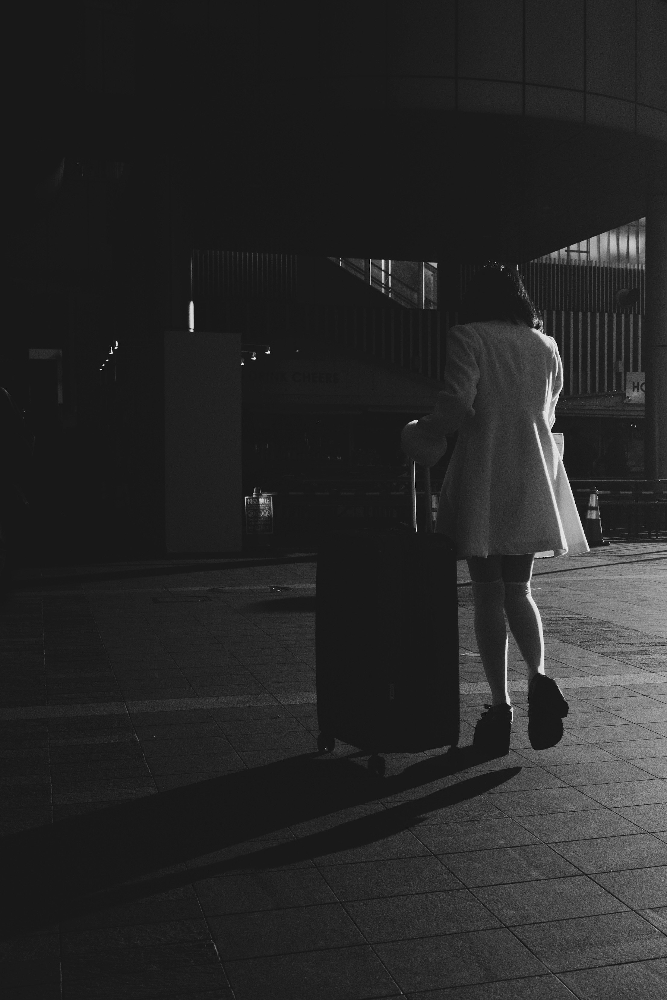 A woman pulling a suitcase at night in a city